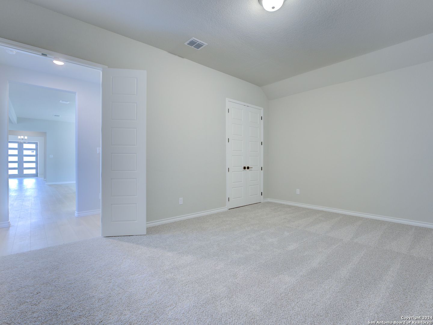 Spacious empty bedroom with open closet doors and foyer view in Davidson Homes The Summerlin A, Castroville Texas