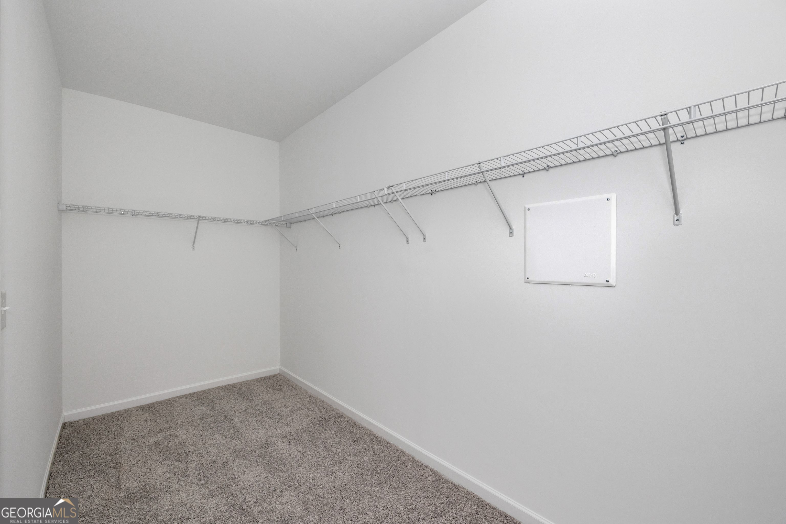 Spacious walk-in closet featuring wire shelving and carpeted floor in Evermore Homes The Luna, Ivy Glen, Perry, Georgia