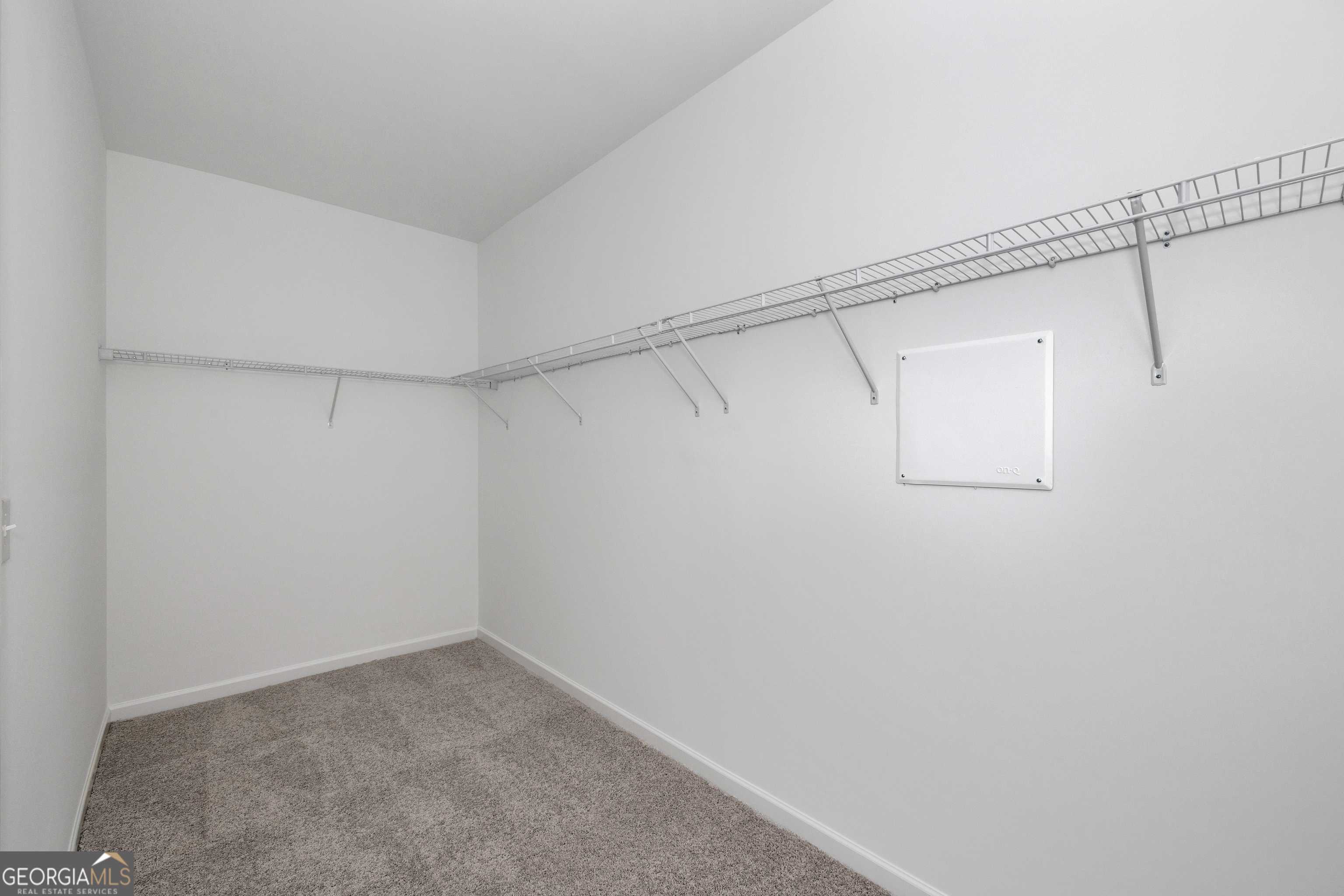 Spacious walk-in closet with wire shelving and carpeted floor in Evermore Homes The Luna, Ivy Glen, Perry, Georgia