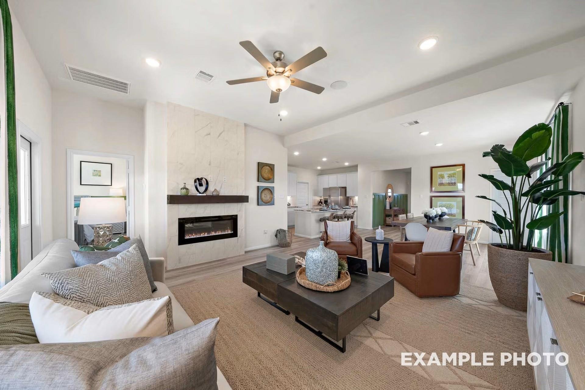 Cozy living room featuring modern gas fireplace, sectional sofa, ceiling fan, and open kitchen in Davidson Homes The Tierra B, Beasley, Texas