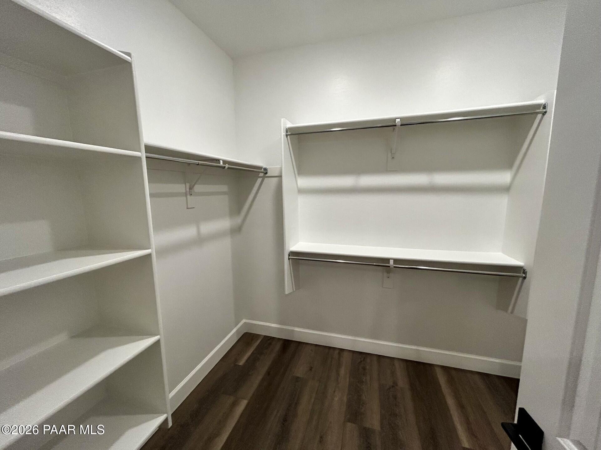 Walk-in closet with white shelving and wood-look flooring in The Harmony C floor plan at Pronghorn Ranch, Prescott Valley.