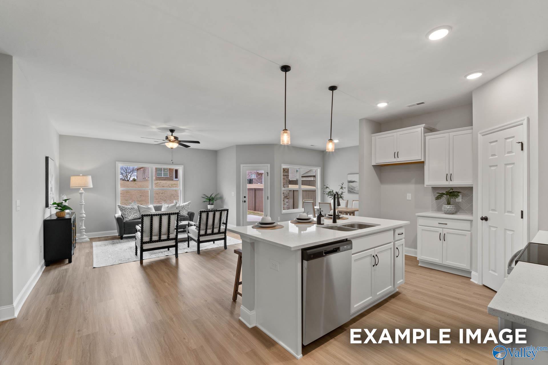Open-concept kitchen and living room in The Daphne C floor plan by Davidson Homes, featuring white island, stainless appliances, hardwood floors, Owens Cross Roads