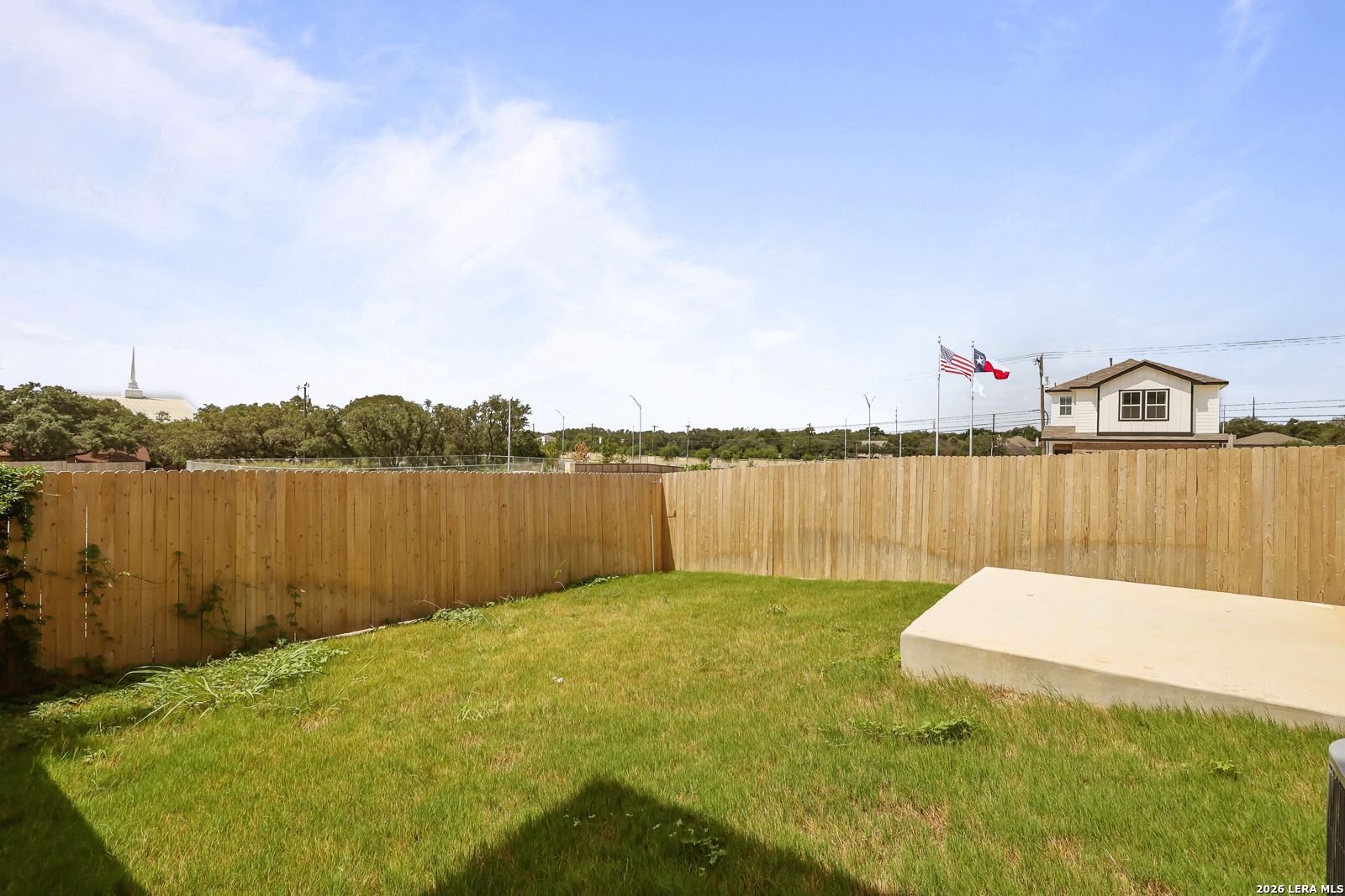 Private backyard with wooden privacy fence and concrete patio in Meadows at Oak Creek, San Antonio, Texas.