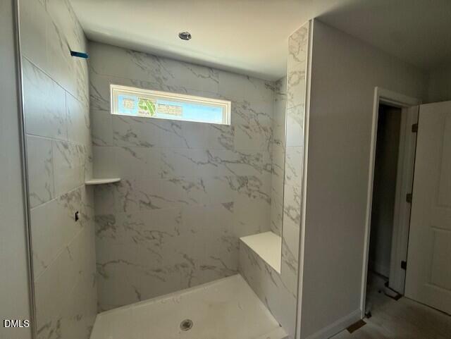 Luxurious walk-in shower with white marble tiles, built-in bench, and window in master bath, Hickory II C, Zebulon NC