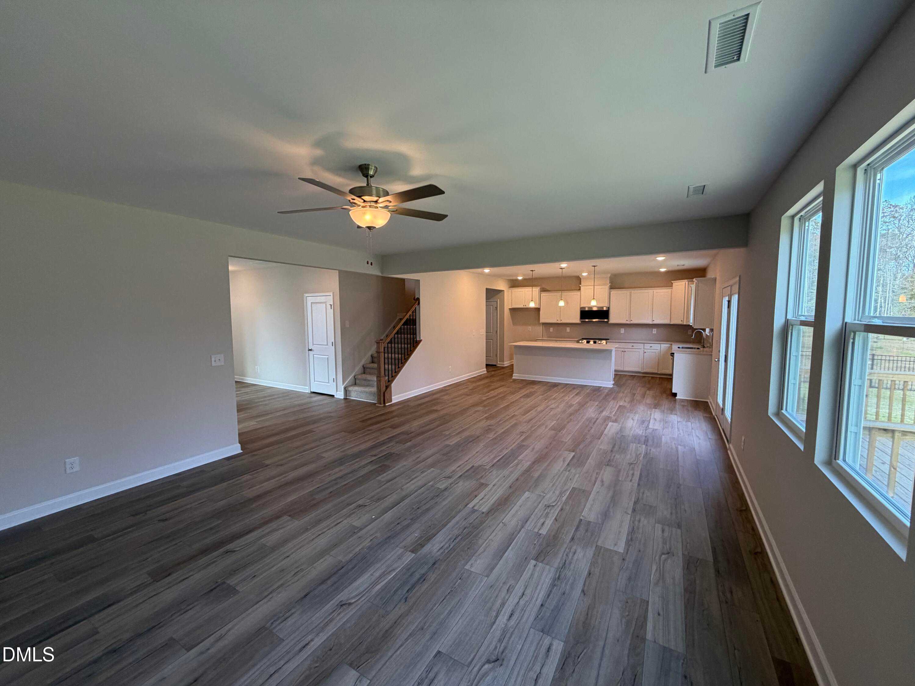 Open-concept living and kitchen area with hardwood floors, white cabinets, island, and ceiling fan in The Hickory II A, Lillington, NC