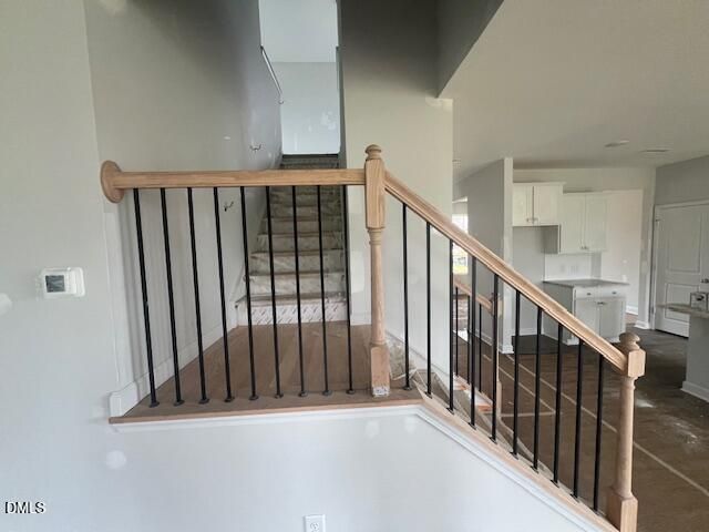 Modern staircase with wood railing and metal balusters in The Ash B floor plan at Retreat at North Main, Lillington, NC.