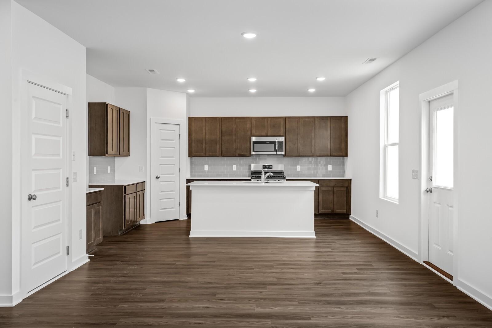 Modern kitchen with shaker cabinets, white quartz island, stainless microwave in The Logan C 3-bedroom home, Sage Farms, White House, TN