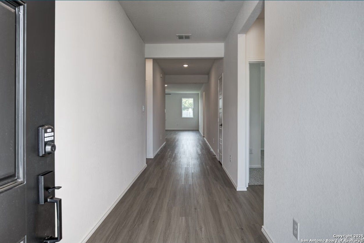 Spacious entry hallway with luxury vinyl plank flooring and white walls in Davidson Homes The Daphne H, Seguin, Texas