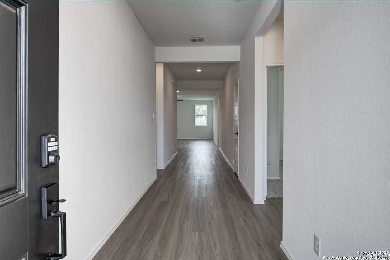 Spacious entry hallway with luxury vinyl plank flooring and white walls in Davidson Homes The Daphne H, Seguin, Texas