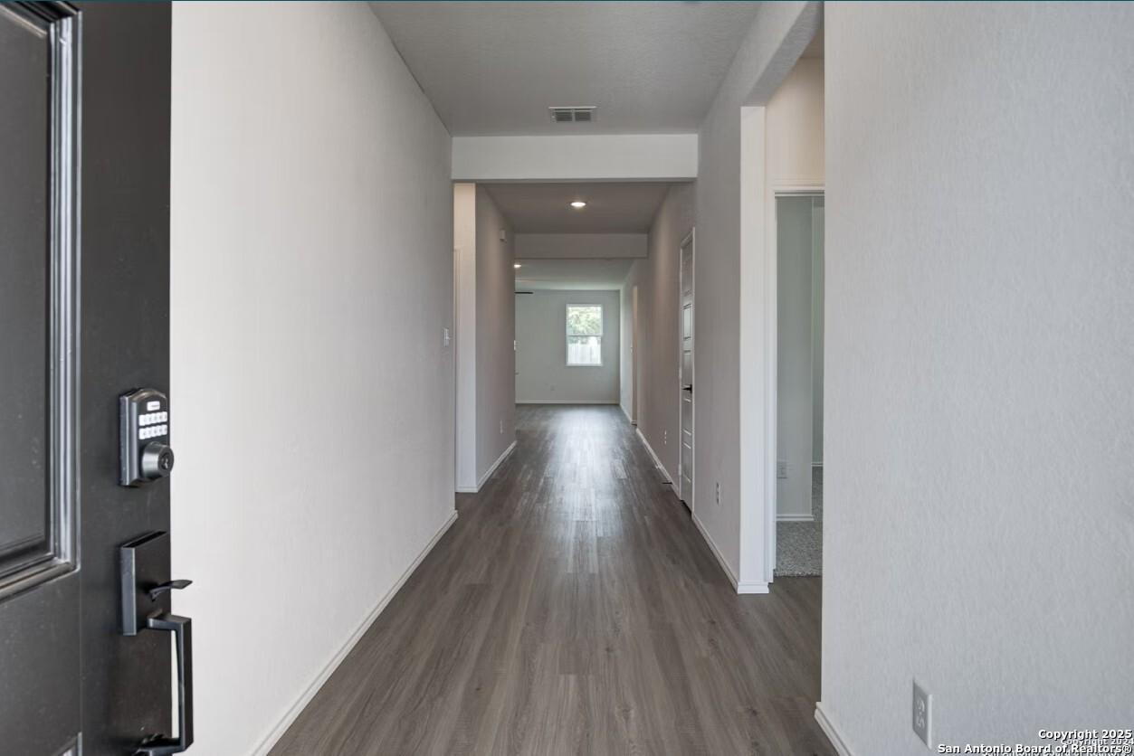 Spacious entry hallway with luxury vinyl plank flooring and white walls in Davidson Homes The Daphne H, Seguin, Texas