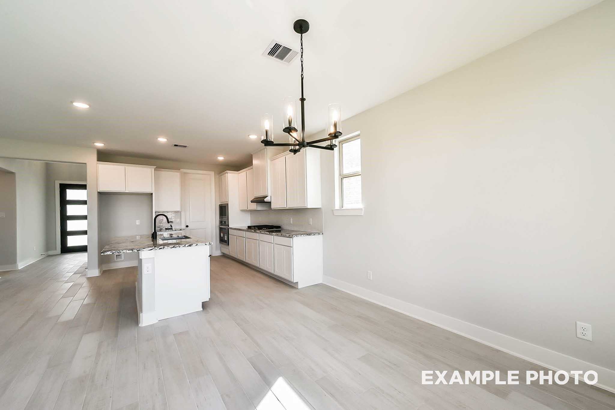 Modern open-concept kitchen with white island, stainless appliances, and chandelier in 4-bedroom Davidson Homes The Philip C, Rosharon, Texas