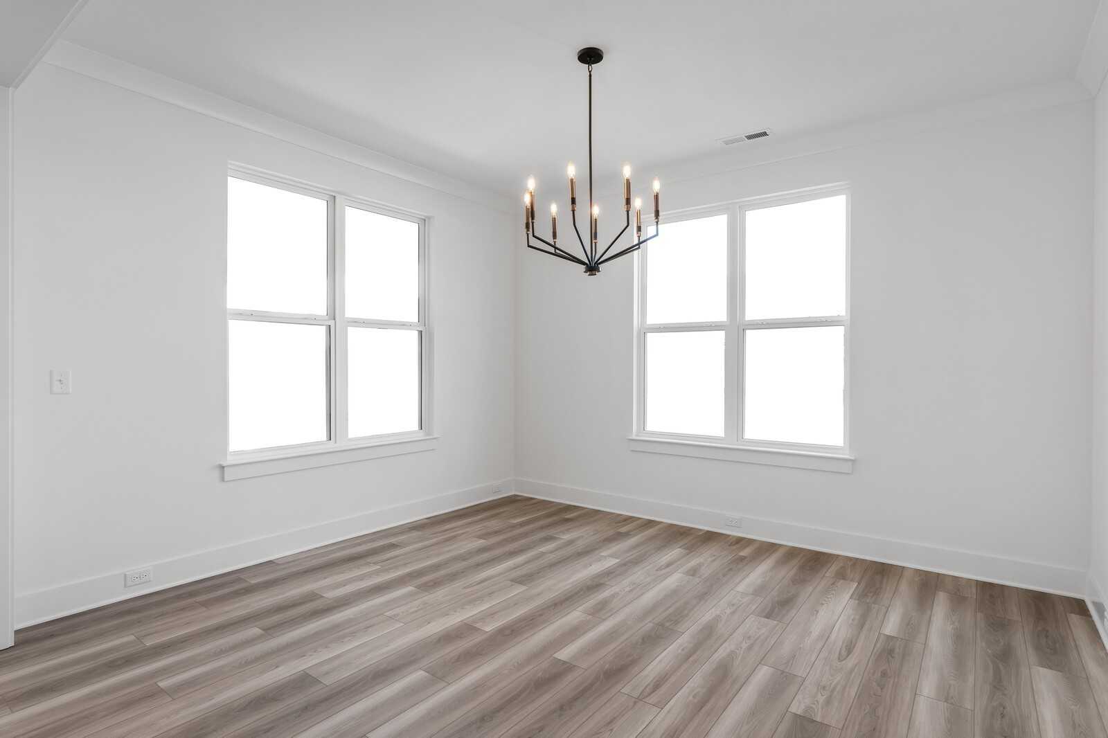 Bright dining room with hardwood floors, large windows, and bronze chandelier in The Hathaway 4-bedroom home, Murfreesboro, TN