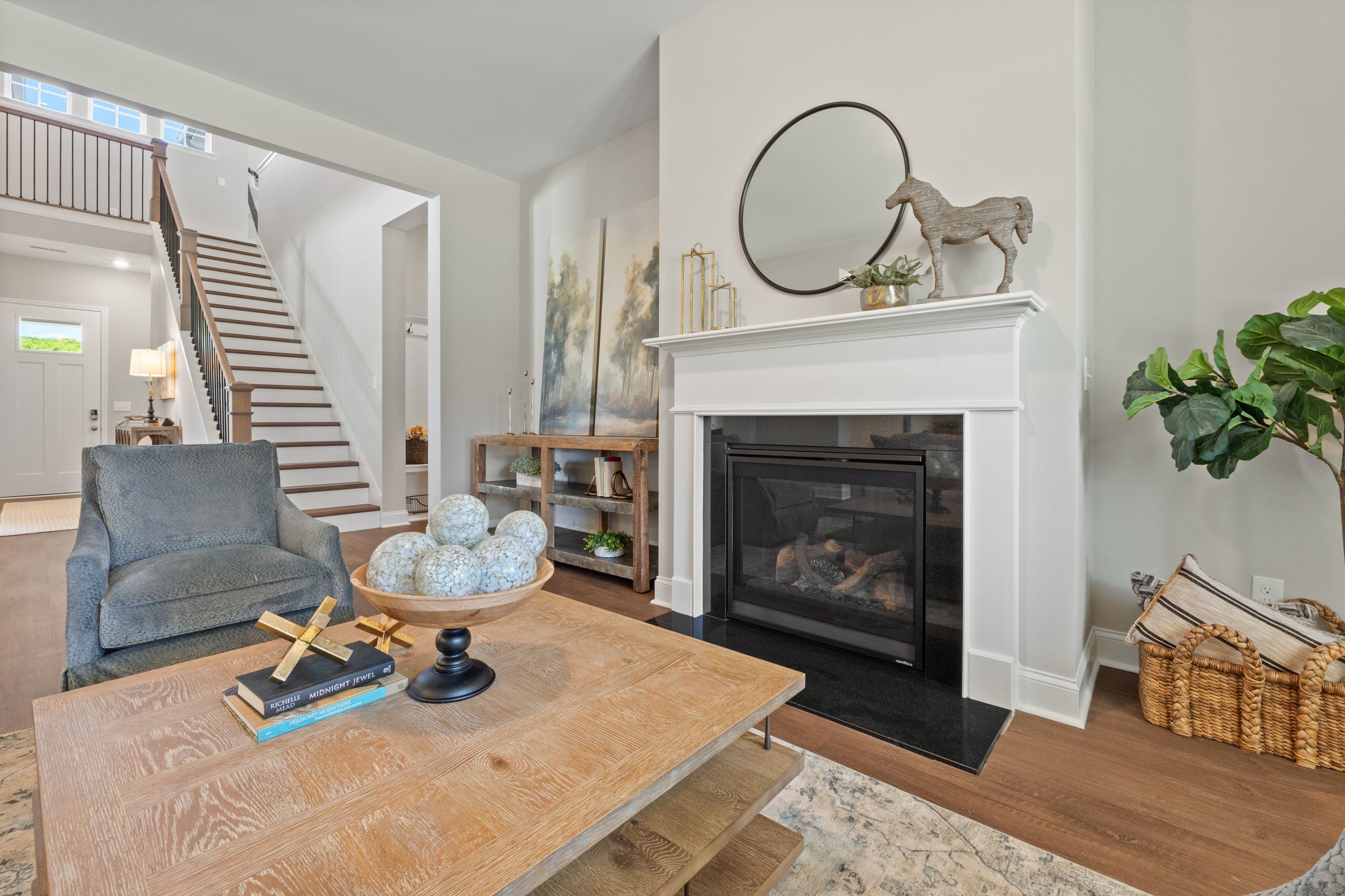 Cozy living room in The Haven D featuring white gas fireplace, wooden coffee table, armchair, and open staircase