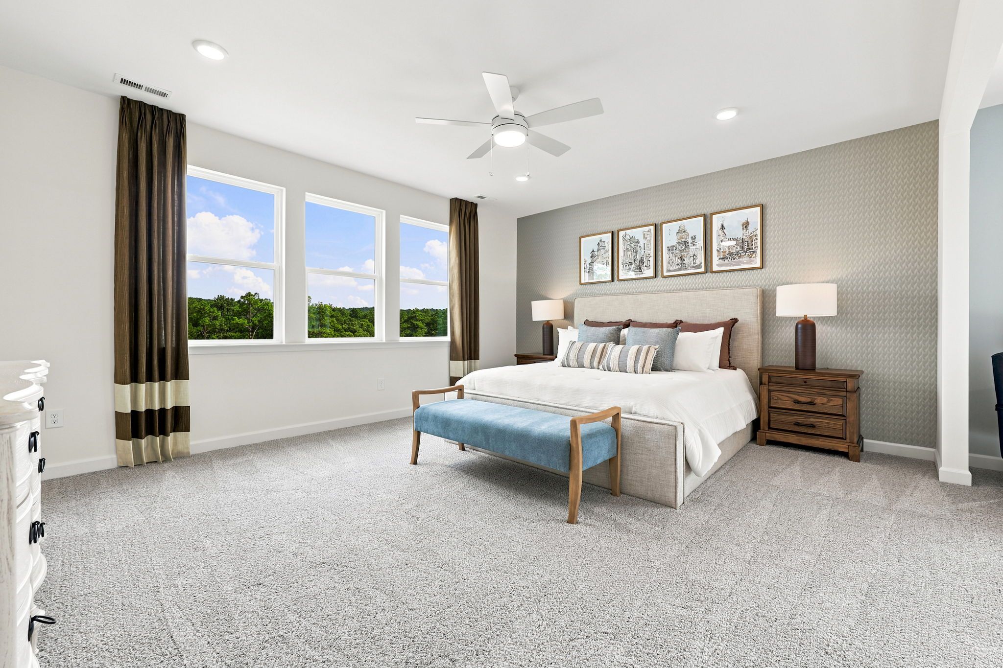 Spacious primary bedroom at Montrose in Aberdeen, NC by Davidson Homes with king bed, accent wall, and large windows.