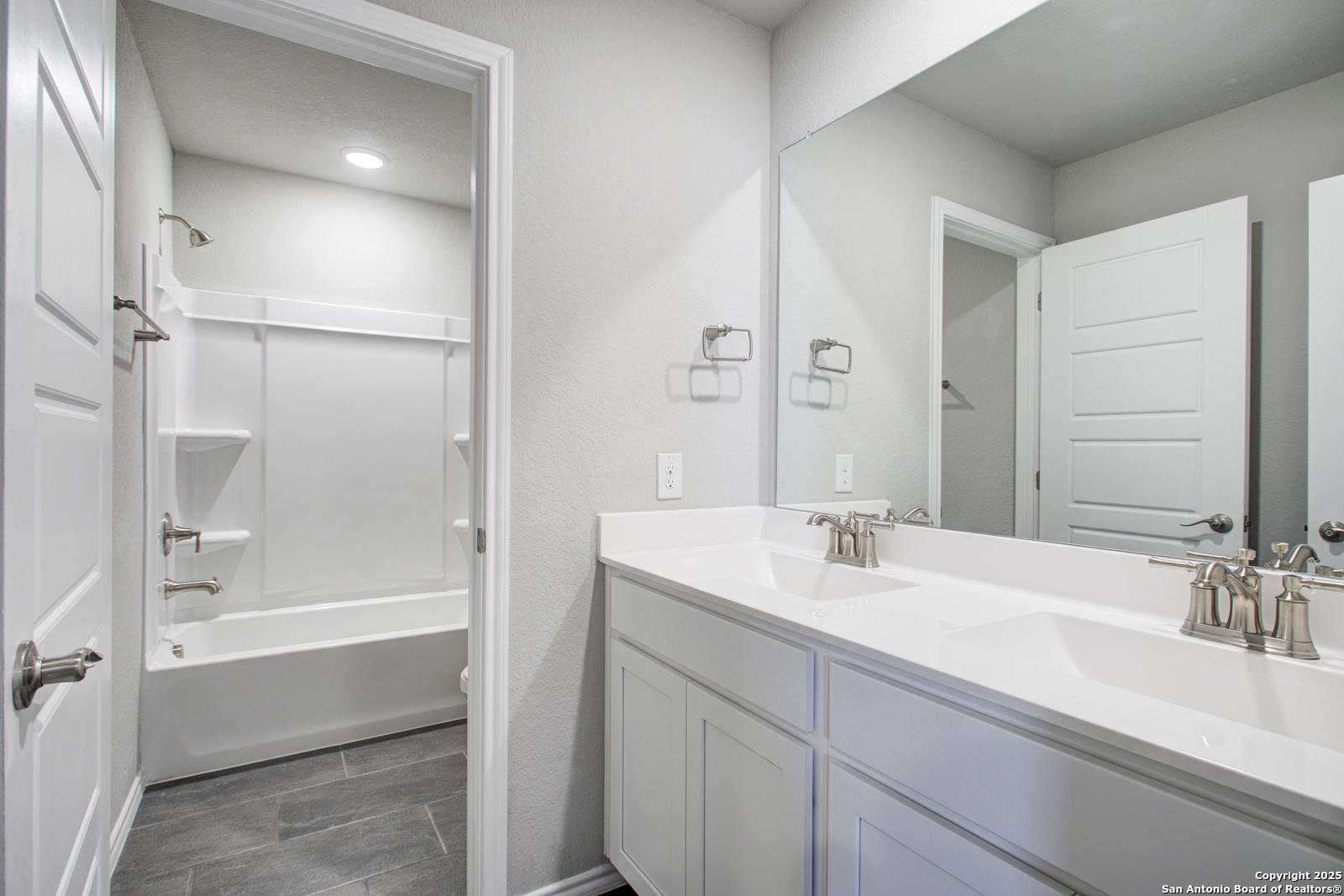 Modern bathroom with double vanity sinks, freestanding tub, and shower in Davidson Homes The Douglas G, San Antonio