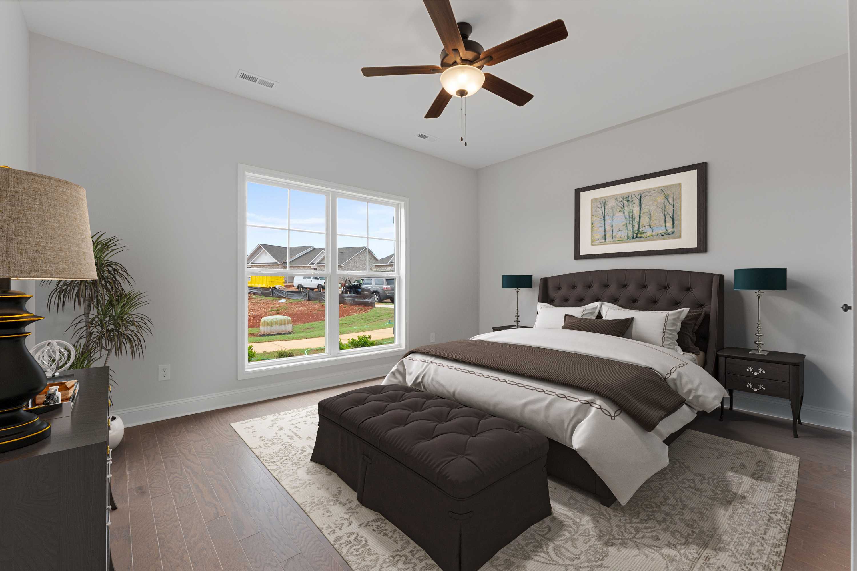 Spacious bedroom at The Villas at Barnett's Crossing in Madison Alabama featuring king bed, ceiling fan, and hardwood floors