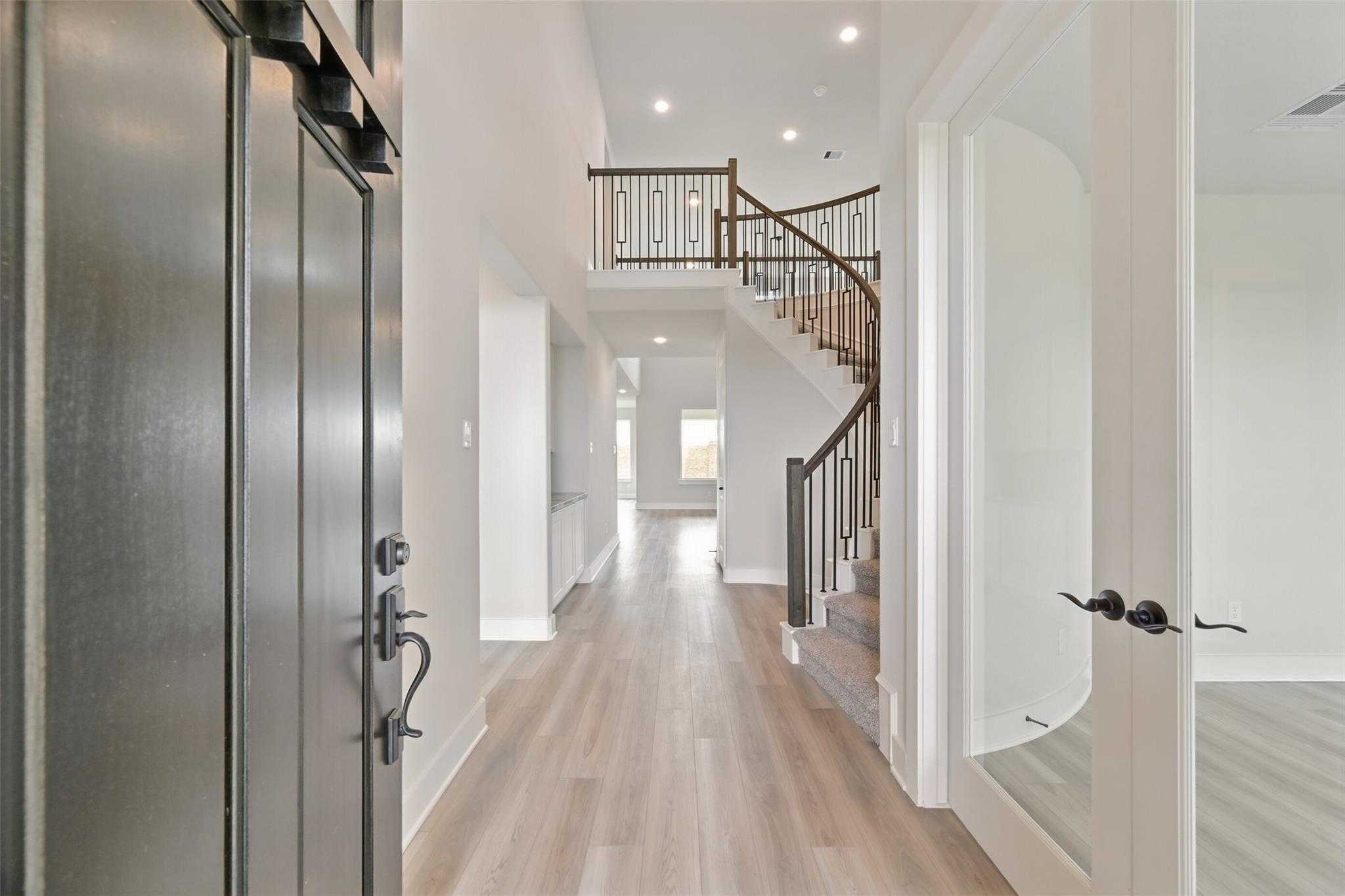 Grand curved staircase in elegant foyer with hardwood floors, Davidson Homes Victoria C in Lago Mar, Texas City