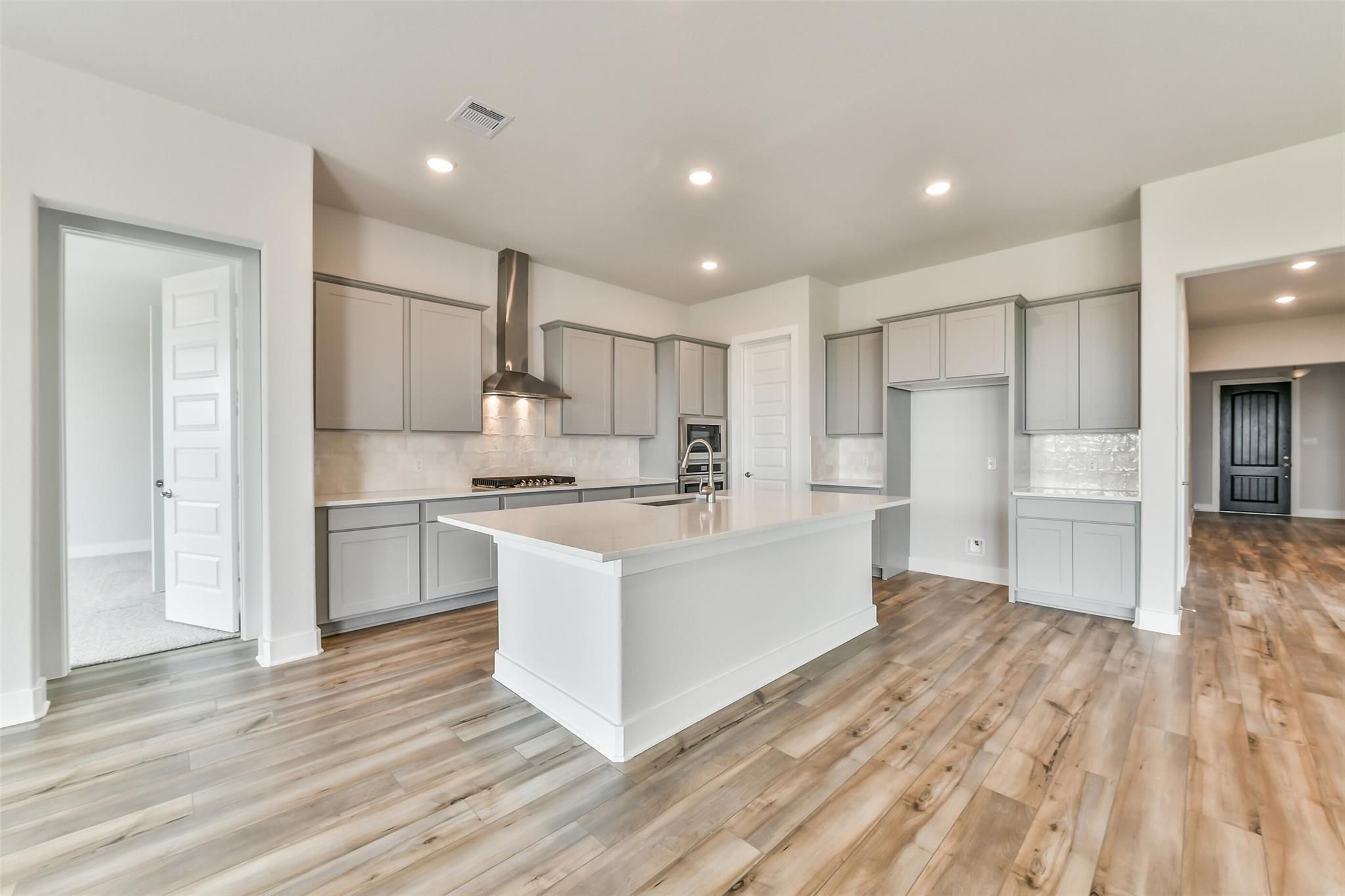 Spacious modern kitchen with white quartz island, gray shaker cabinets, stainless steel appliances in Davidson Homes The George A, Lago Mar, Texas City
