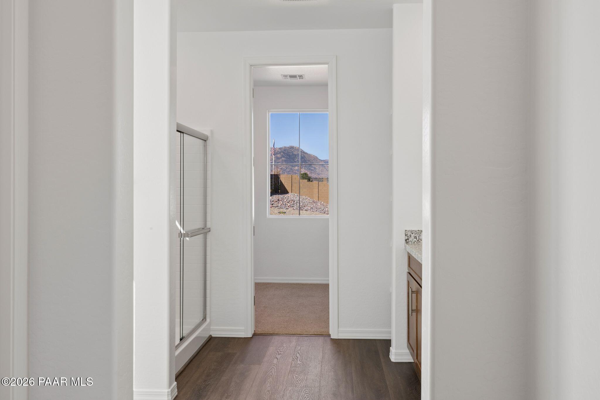 Bright bathroom featuring desert mountain view, white walls, wood floors, and vanity in Davidson Homes The Monarch A, Prescott, AZ