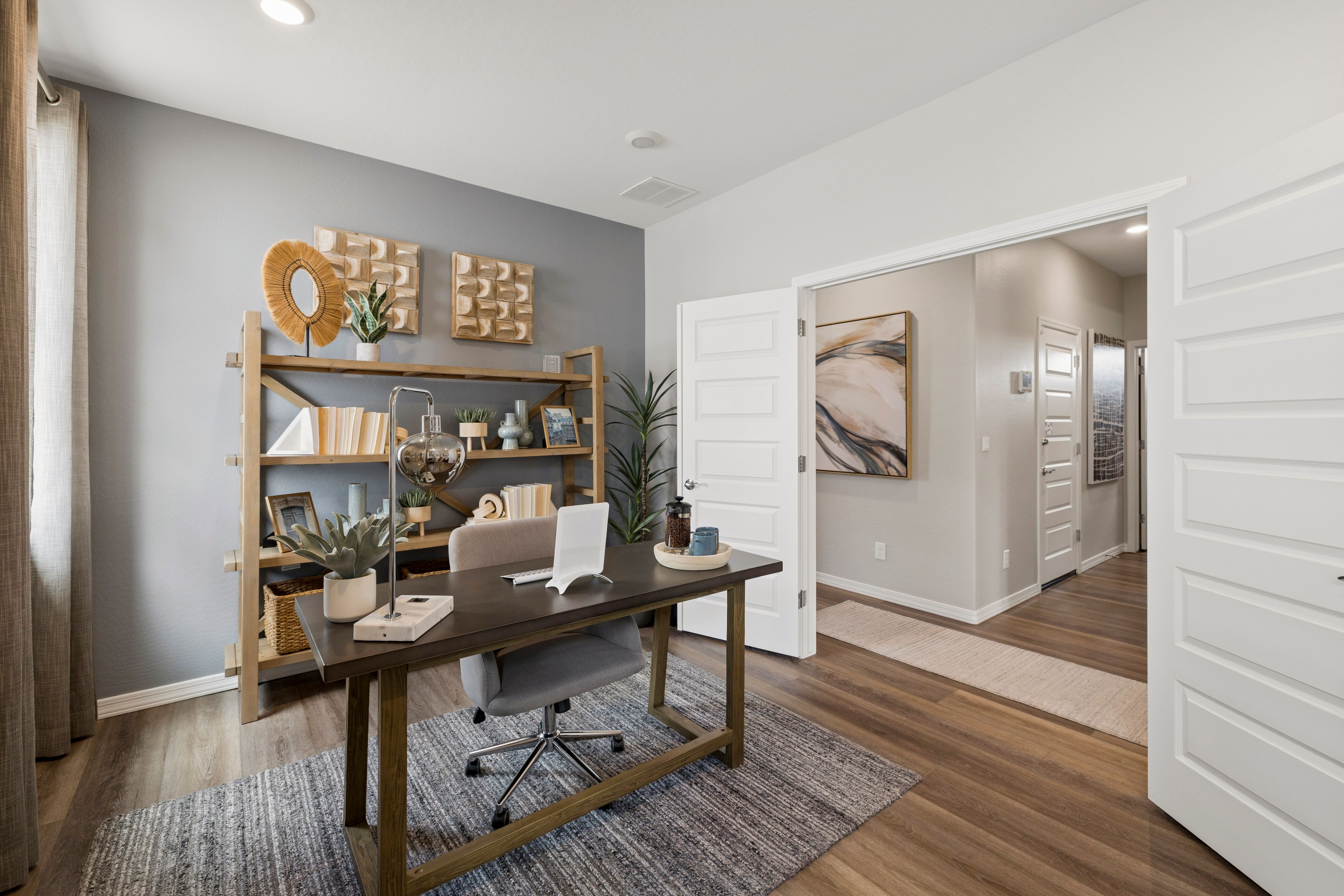 Modern home office at South Ranch Destination Collection in Prescott AZ with wooden desk, bookshelf, plants, and abstract wall art