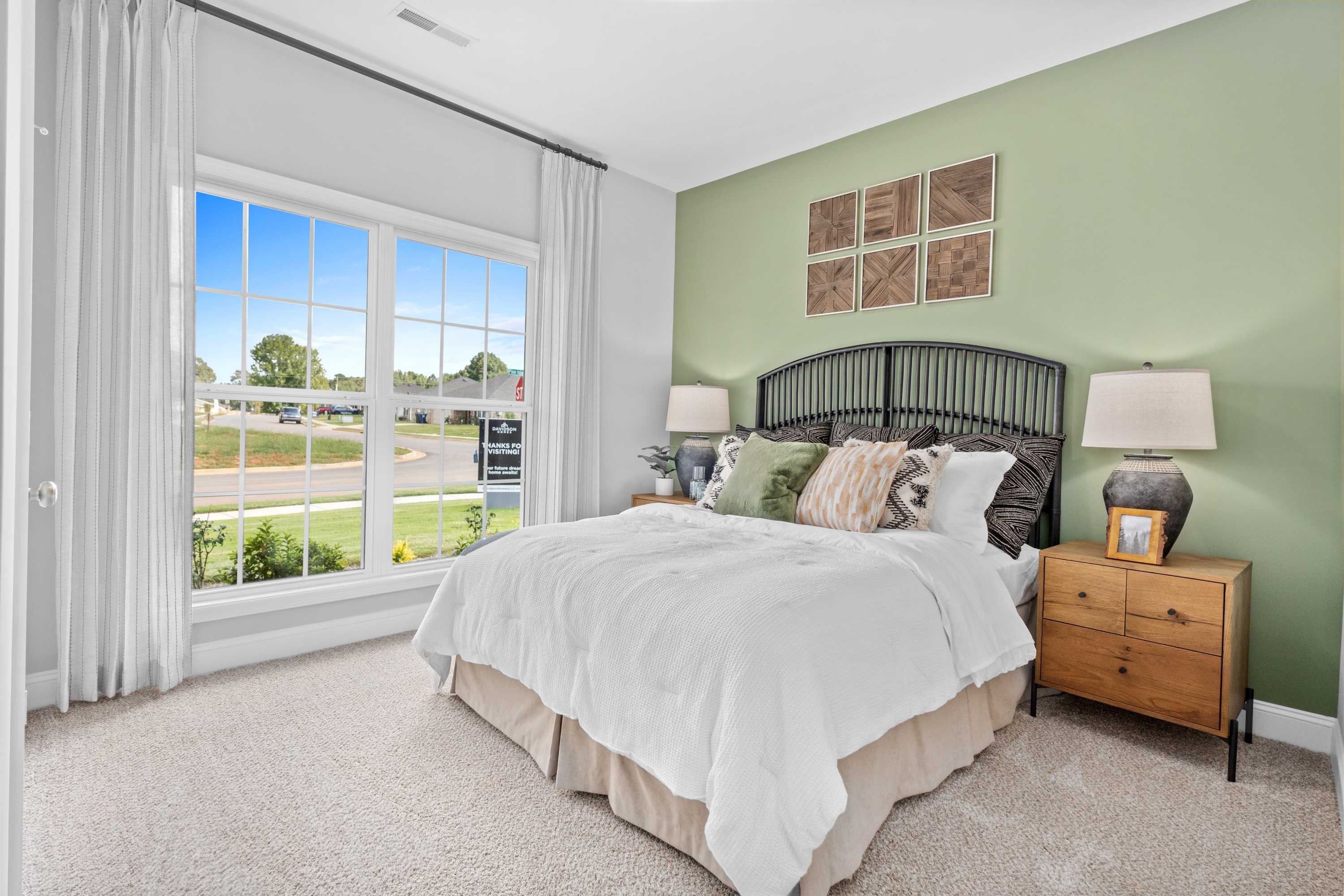 Spacious master bedroom at Wood Trail in Toney Alabama with large window, green accent wall, king bed, wrought iron headboard