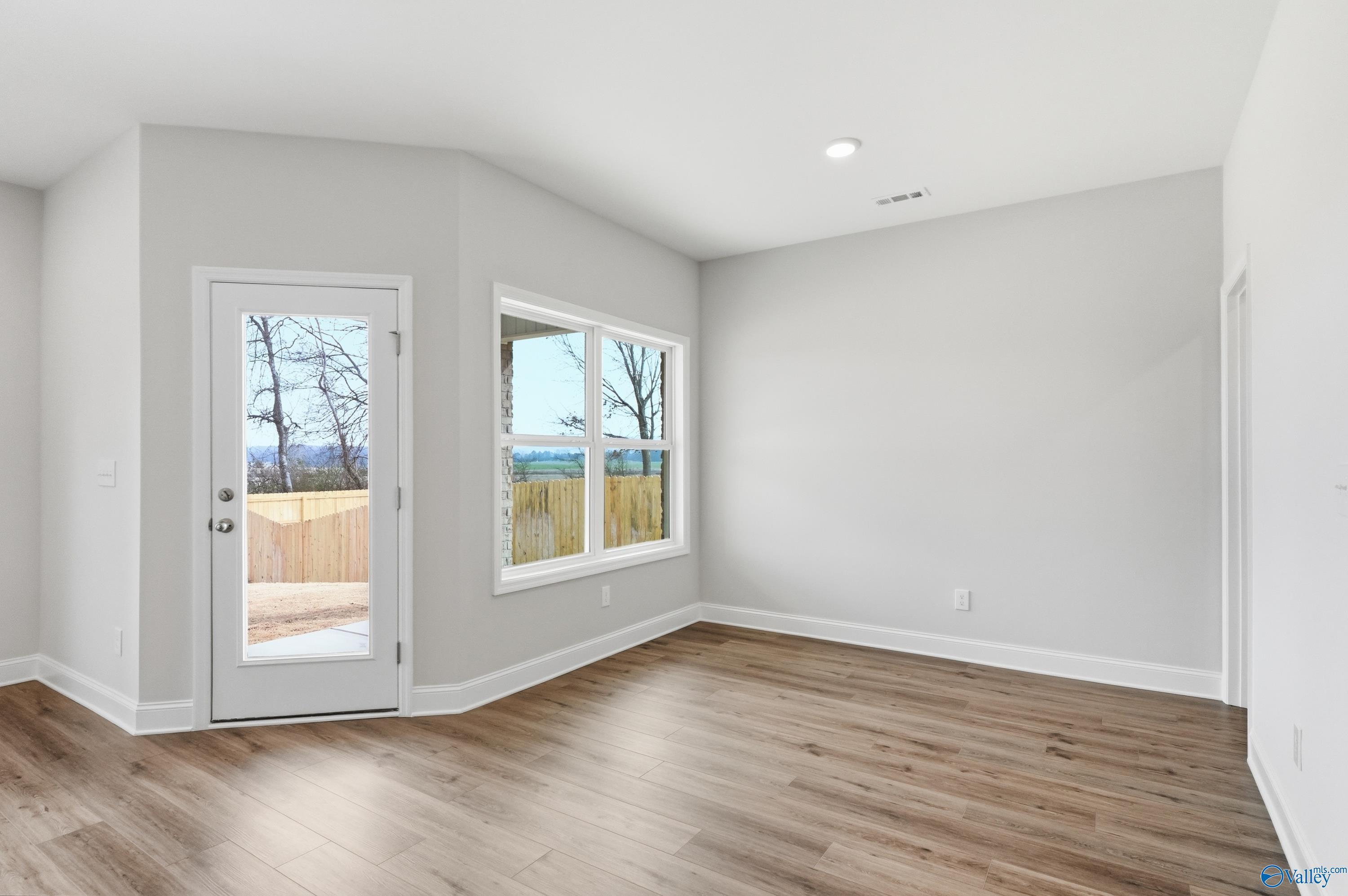 Bright family room with gray walls, large windows, sliding door to wooded backyard in 4-bedroom Davidson Homes The Daphne C, Toney Alabama