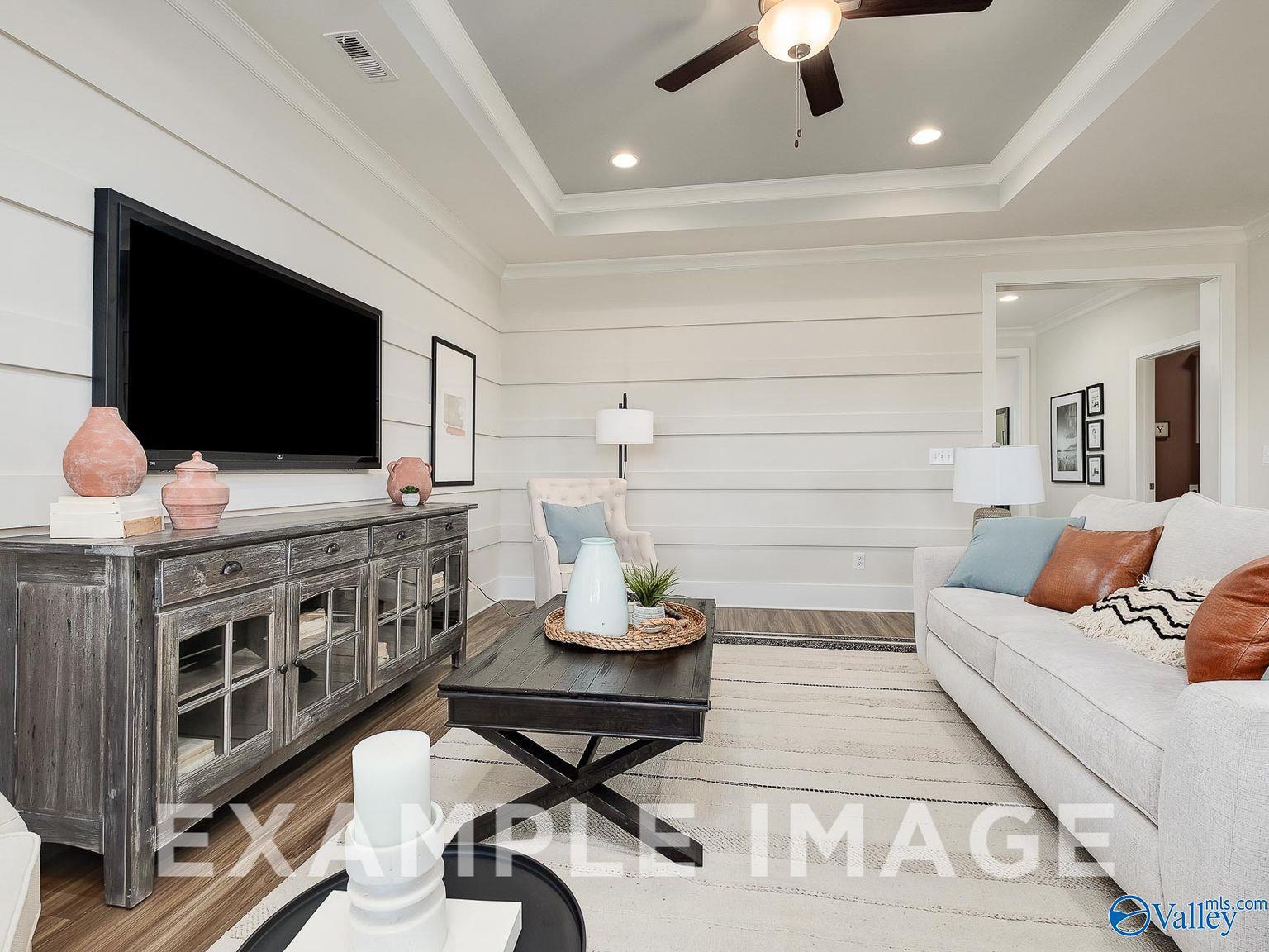 Cozy living room with shiplap walls, wall-mounted TV, wooden console, and plush sofa in Davidson Homes The Everett B, Toney, Alabama