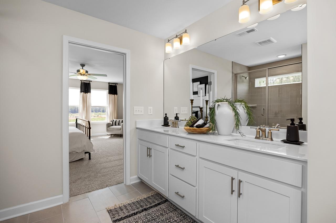 Spacious master bathroom at Wellers Knoll in Lillington NC with double vanity, greenery accents and open bedroom view