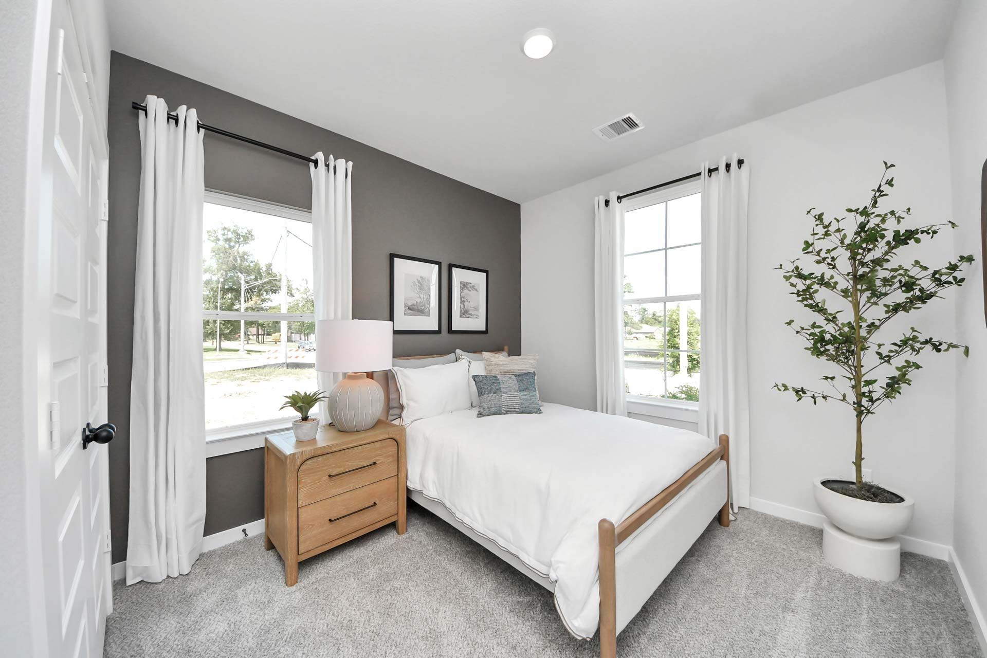 Modern bedroom in Enclave at Newport by Davidson Homes, Crosby TX, featuring a charcoal accent wall and natural wood bed.