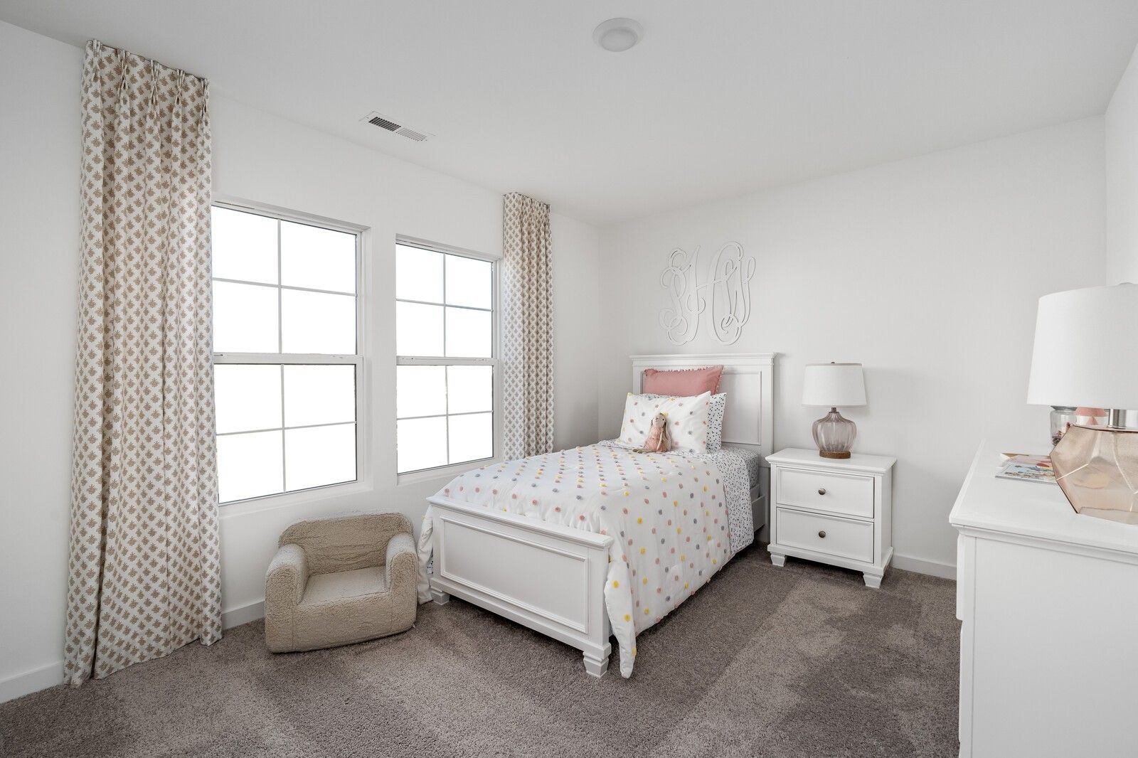 Charming girl's bedroom with white twin bed, pink polka dot bedding, beige curtains, and modern nightstand in Davidson Homes The Cumberland A, Gallatin, Tennessee