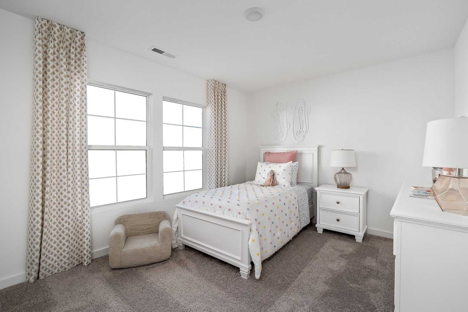 Charming girl's bedroom with white twin bed, pink polka dot bedding, beige curtains, and modern nightstand in Davidson Homes The Cumberland A, Gallatin, Tennessee