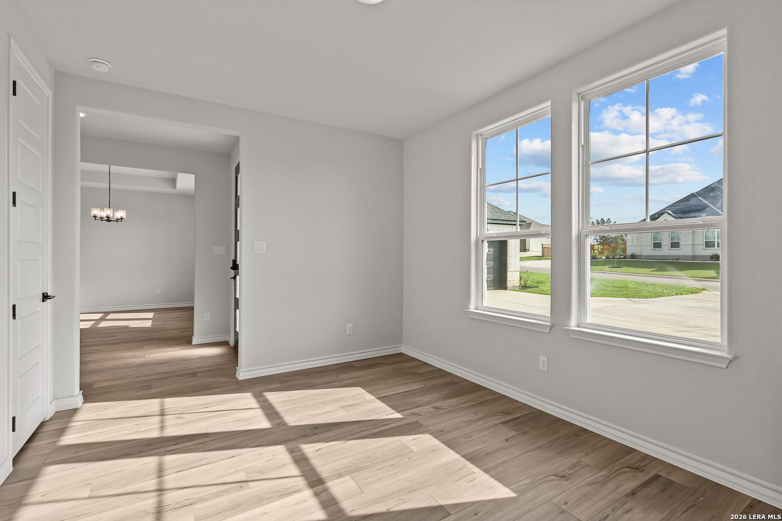 Bright sunlit dining room with wood-look flooring and front-facing windows in Davidson Homes' The Oxford F, Potranco Oaks, Castroville