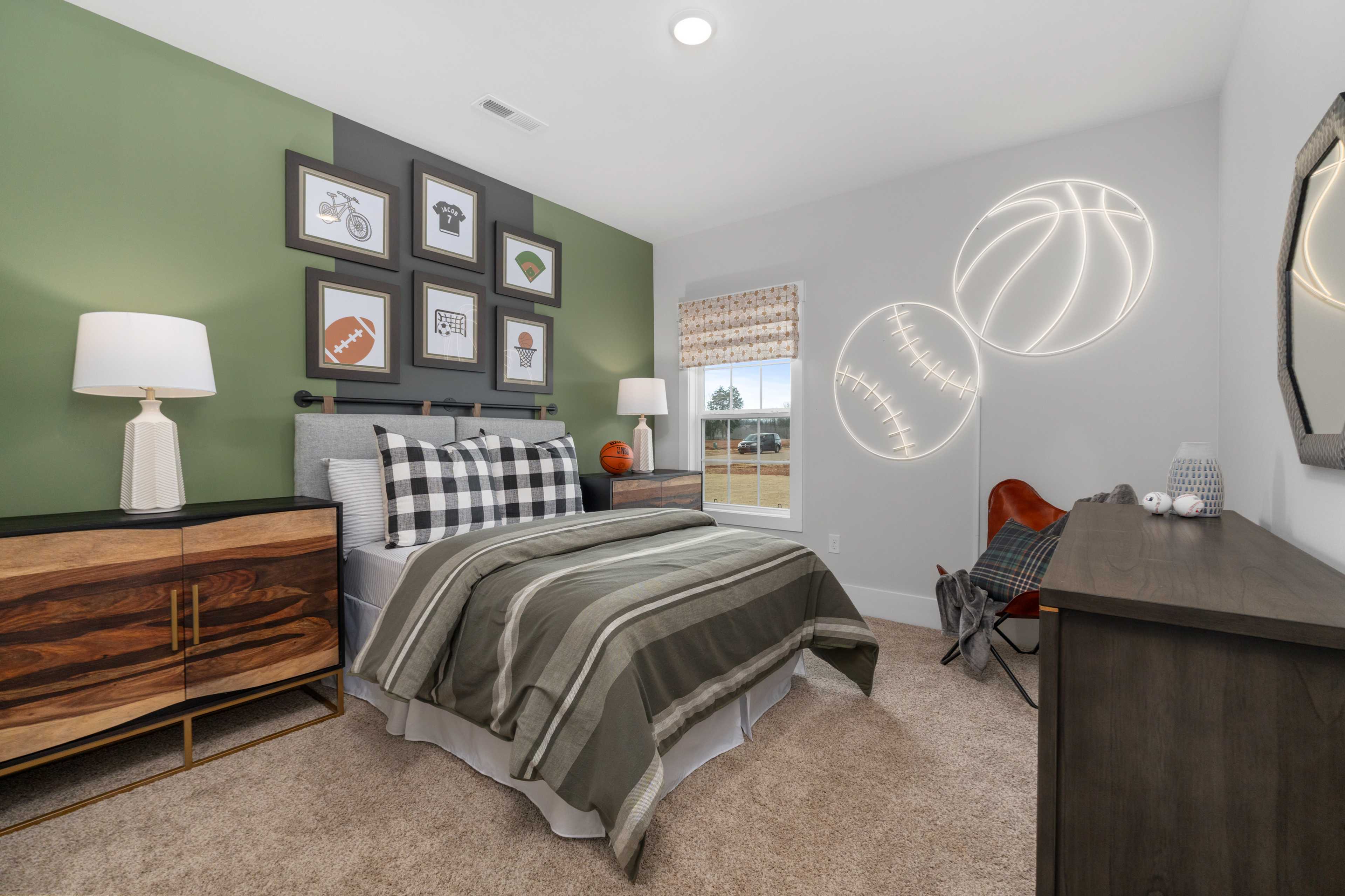 Sports-themed boy's bedroom at Briercreek in Meridianville AL with green accent wall, baseball art, and wooden dresser