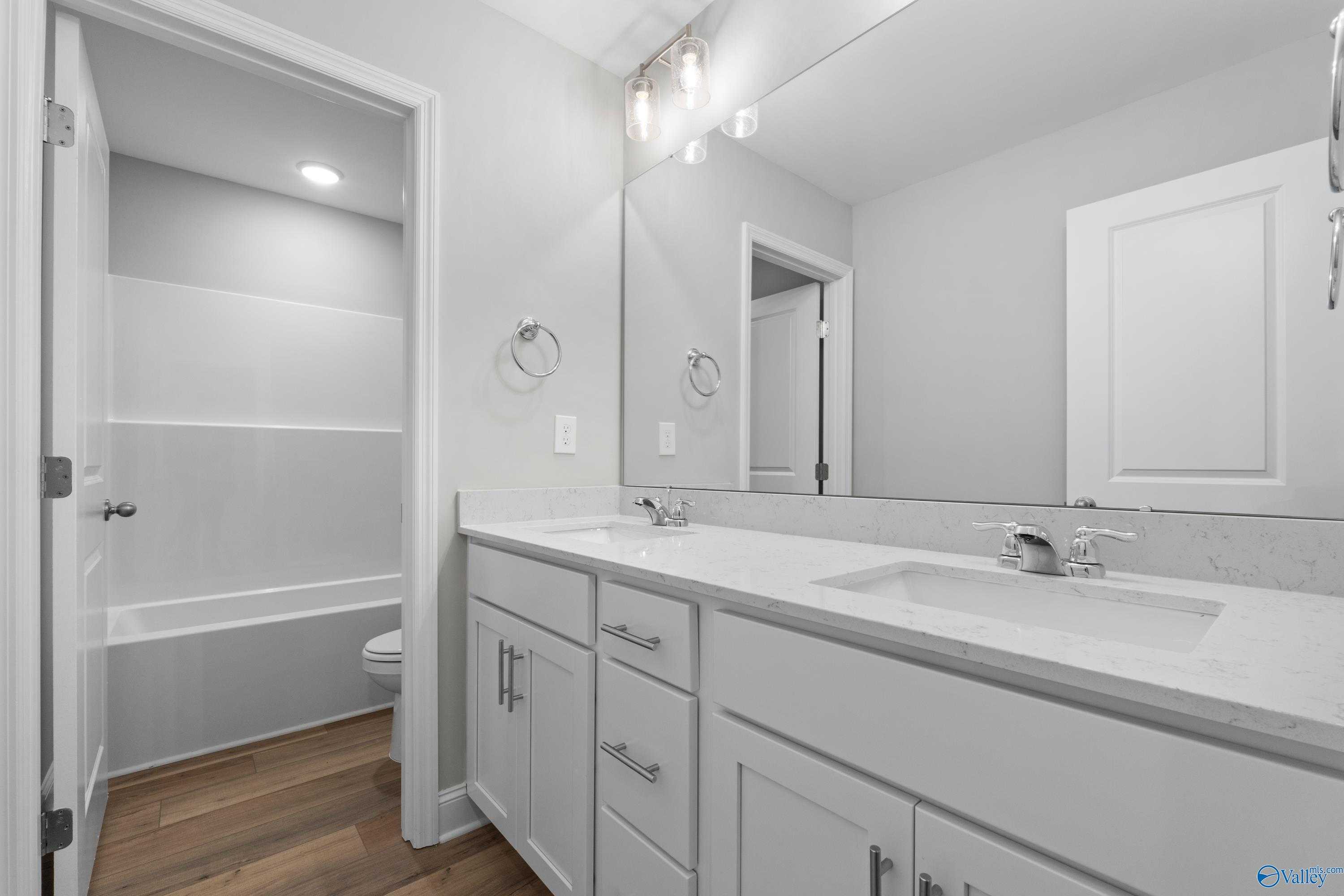 Modern bathroom with double vanity, white quartz countertop, bathtub, and subway tile in 5-bedroom Davidson Homes Chelsea B, New Market, Alabama