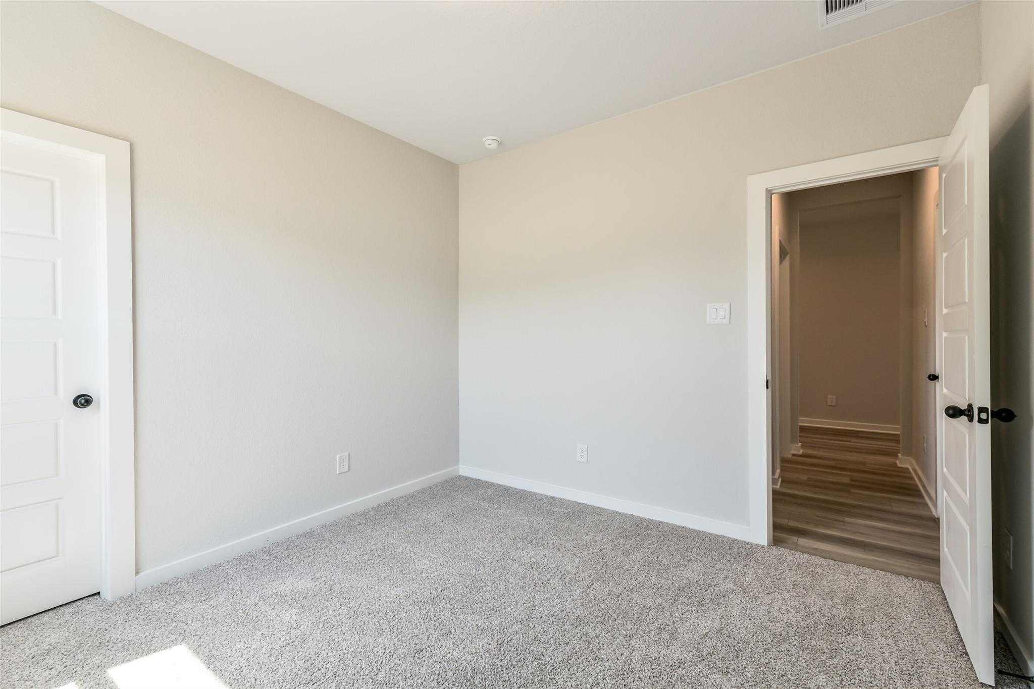 Spacious master bedroom with beige walls, carpeted floors, and en-suite access in Davidson Homes The Daphne H, Crosby, Texas