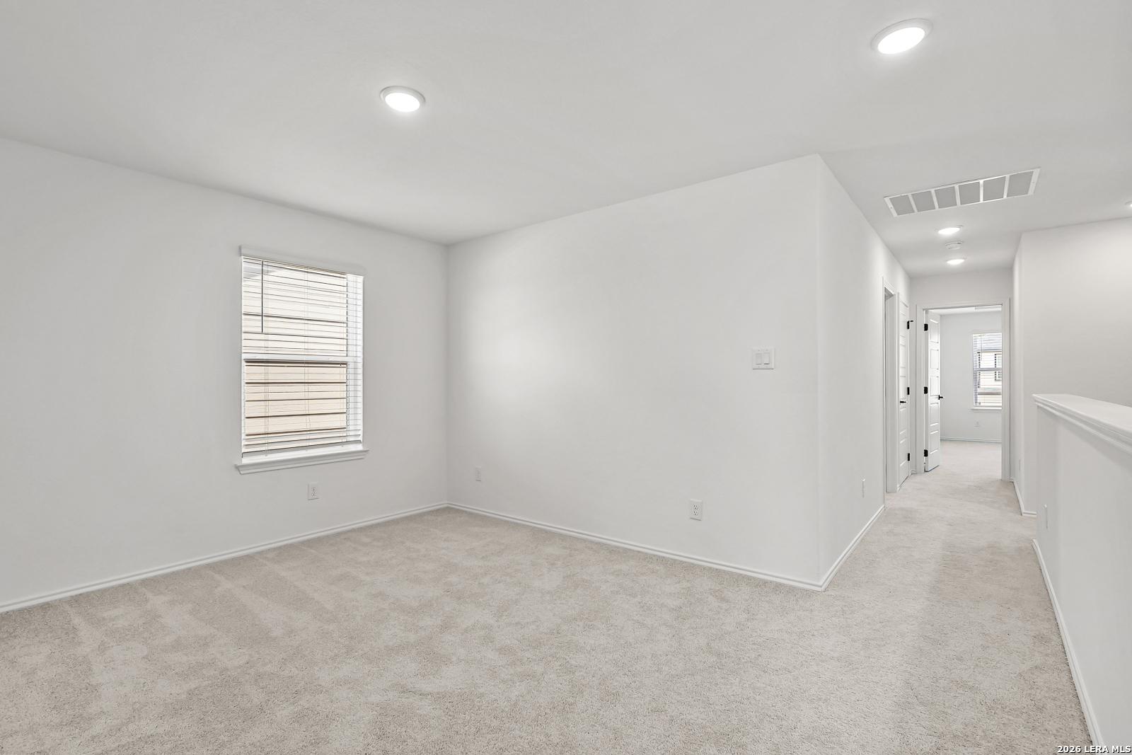 Bright, carpeted bedroom with recessed lighting in The Gillian C floor plan at Meadows at Oak Creek, San Antonio, Texas.