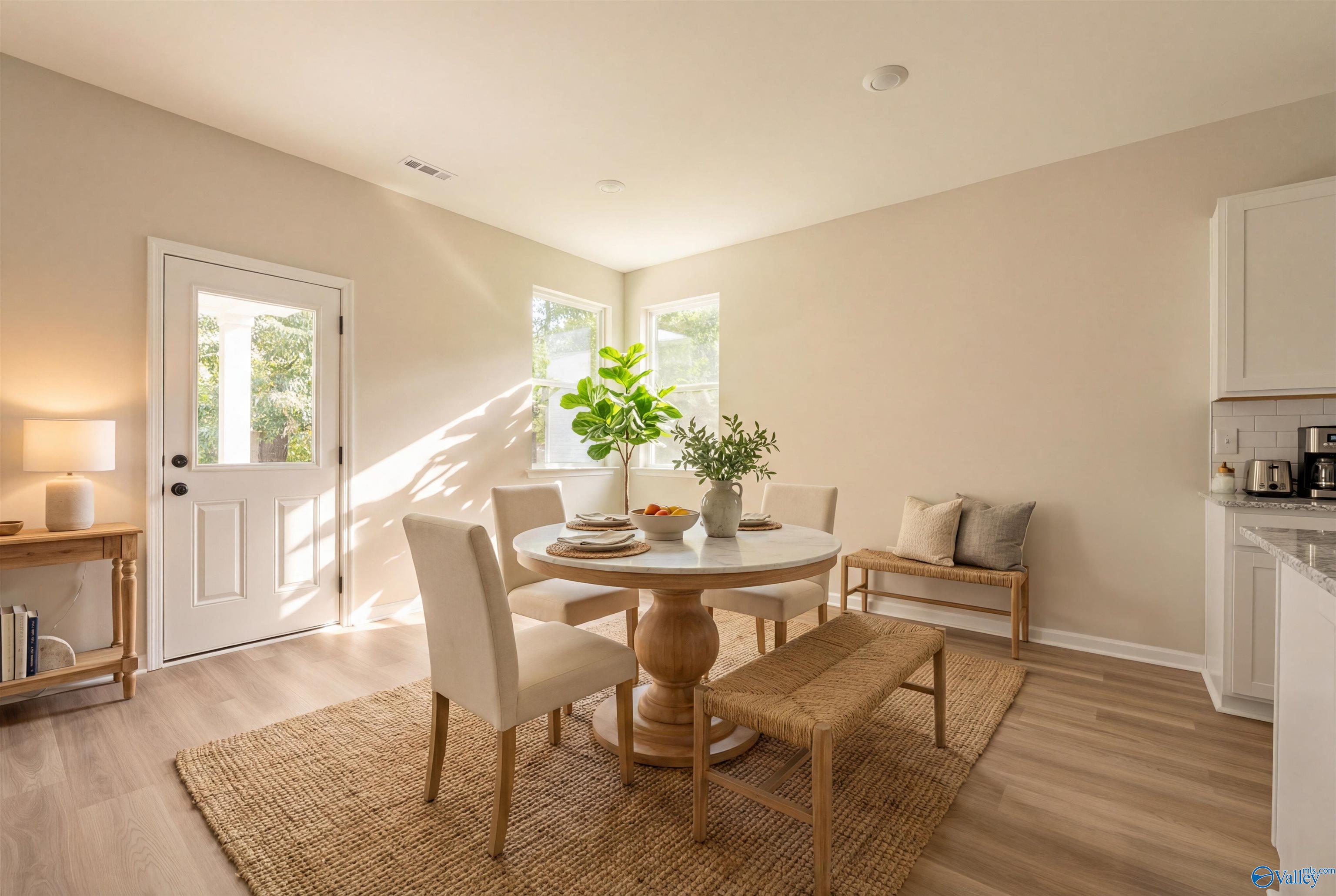 Bright dining nook with round wooden table, upholstered chairs, bench, plants in The Phoenix 3-bedroom home, Davidson Homes, Fayetteville, TN