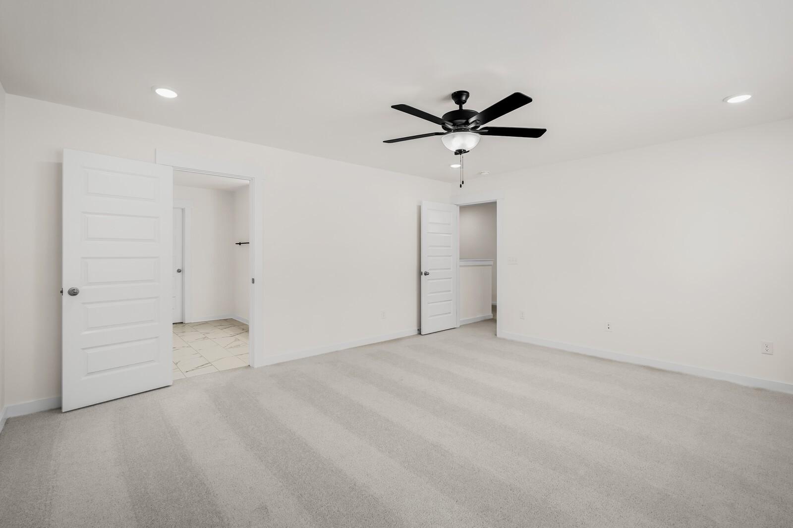 Spacious bedroom with plush carpet and ceiling fan in The Willow floor plan at Woods Crossing in Gallatin, Tennessee.