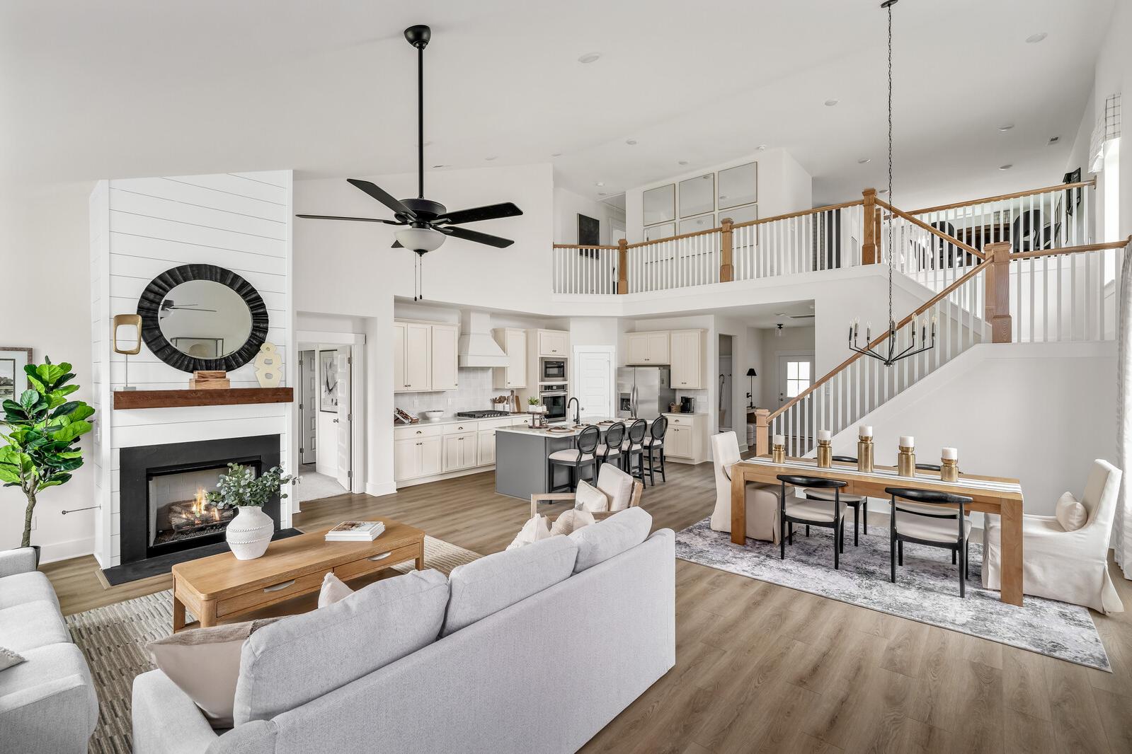 Open-concept living kitchen dining area at Woods Crossing in Gallatin TN with white shiplap walls, fireplace, hardwood floors, and open staircase