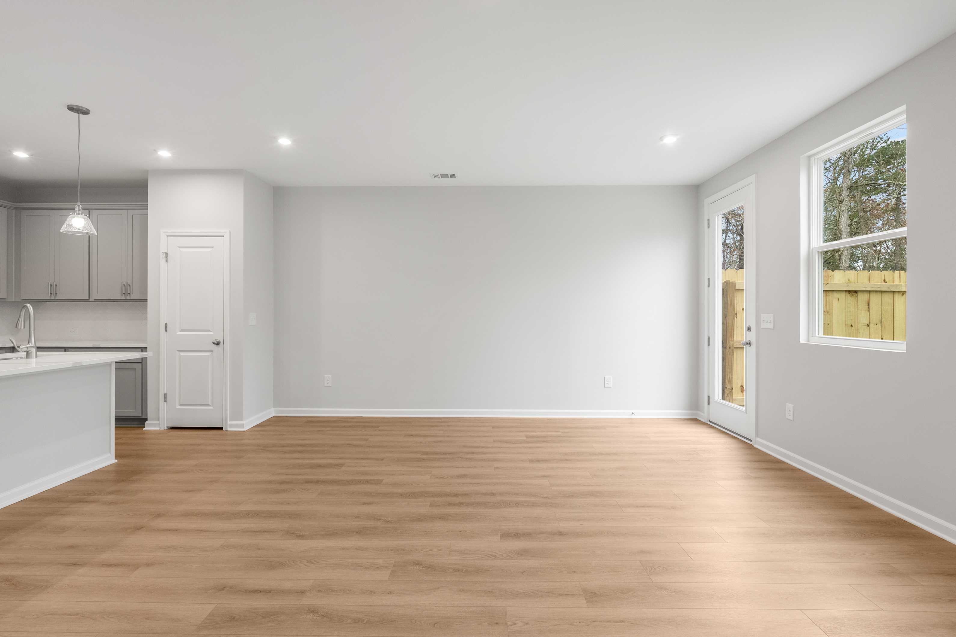 Open-concept kitchen and living area in The Durant A with white cabinets, hardwood floors, and sliding glass doors