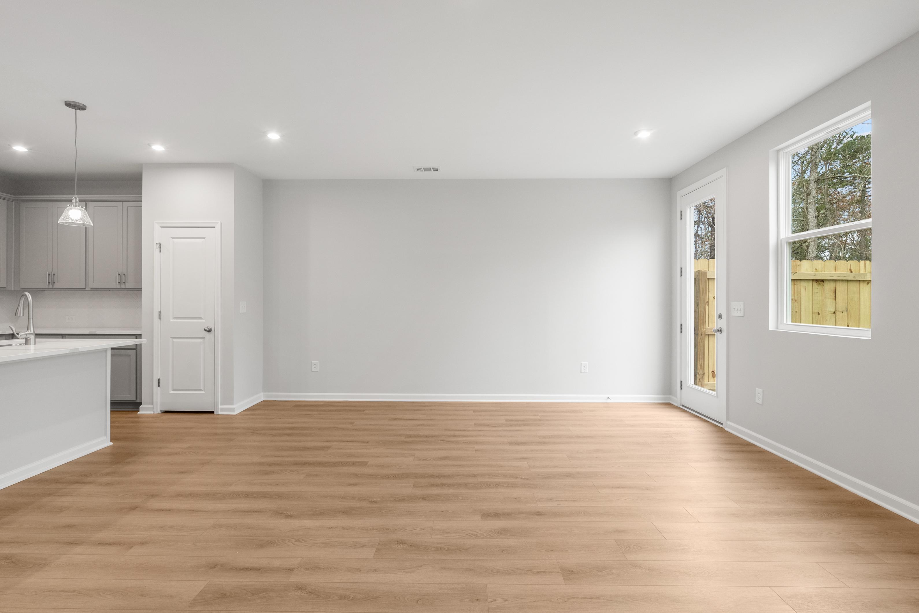 Open-concept kitchen and living area in The Durant A with white cabinets, hardwood floors, and sliding glass doors
