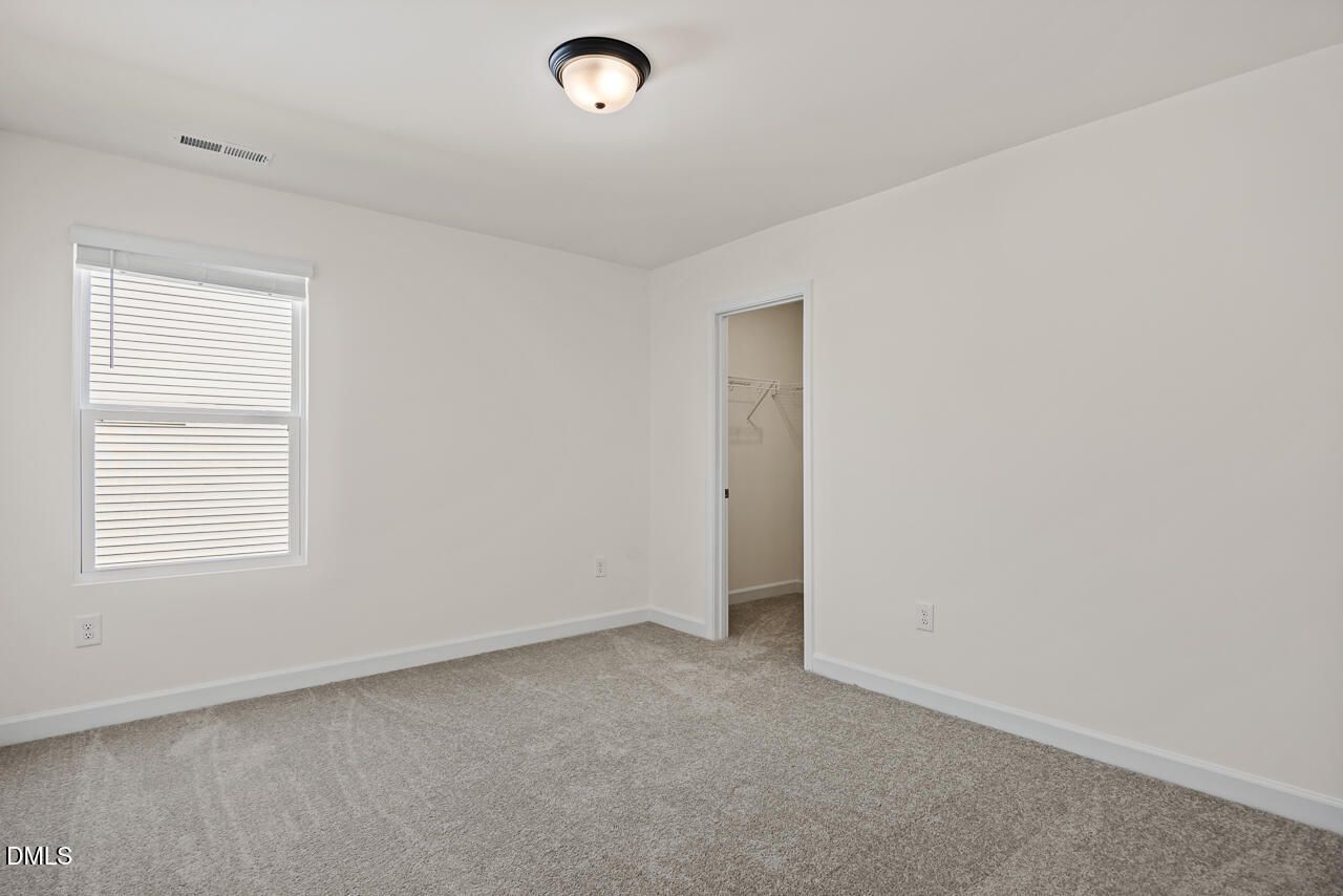 Bright carpeted bedroom with window blinds and walk-in closet in Davidson Homes Hickory II B, Lillington, North Carolina