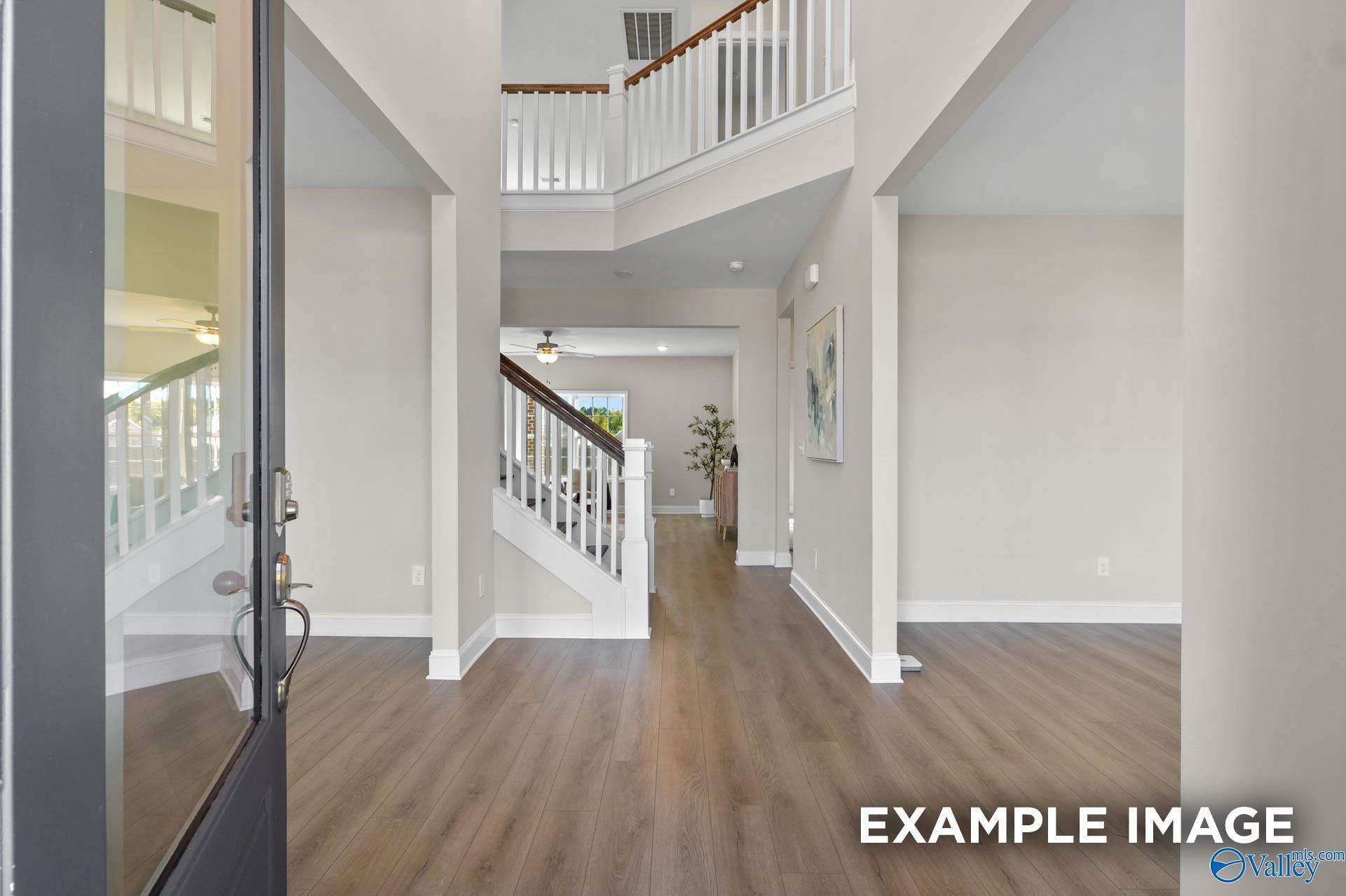 Grand two-story foyer with sweeping wooden staircase and hardwood floors in Davidson Homes The Madison A, Meridianville, Alabama