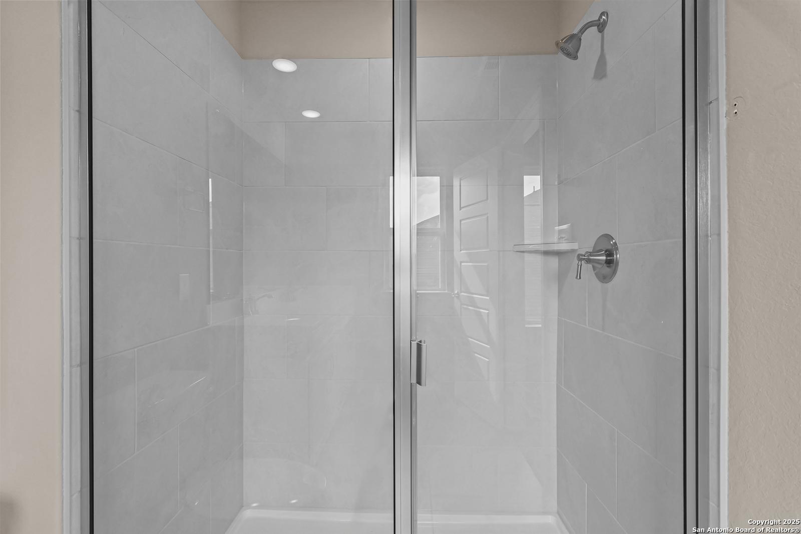 Modern frameless glass shower with white subway tiles, chrome rainfall showerhead in master bath, Davidson Homes The Douglas G, San Antonio