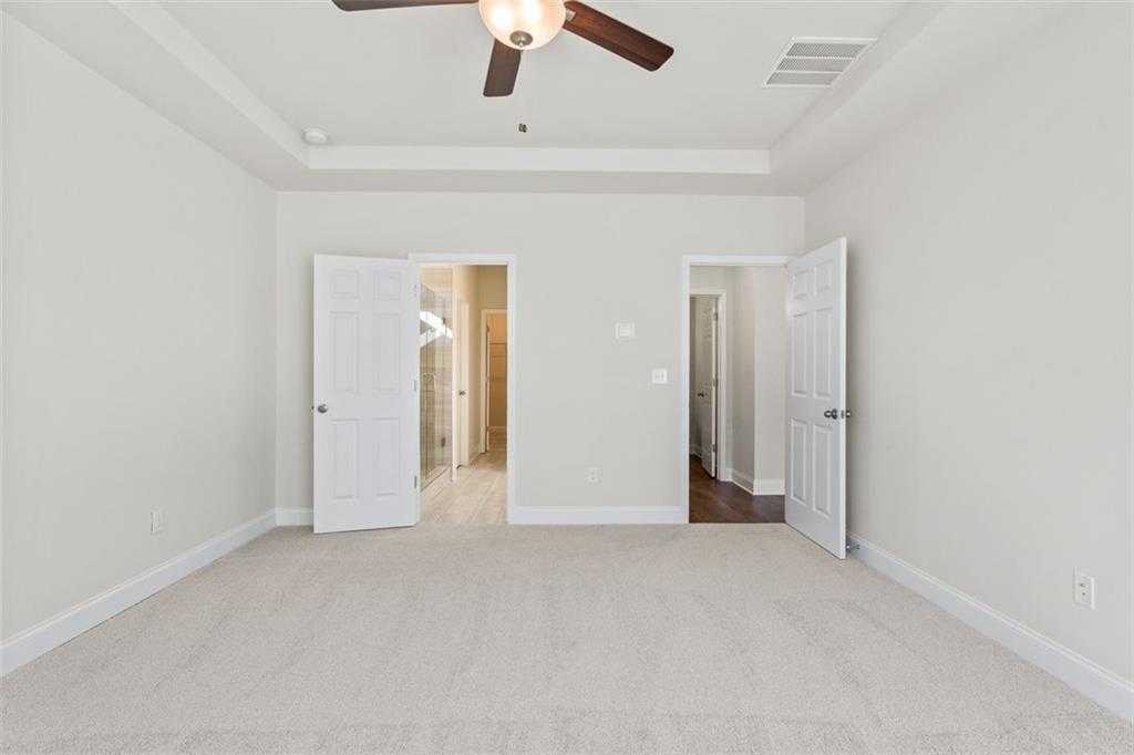 Empty bedroom with open closet and bathroom doors, ceiling fan in Davidson Homes The Ash C at Wehunt Meadows, Hoschton, GA