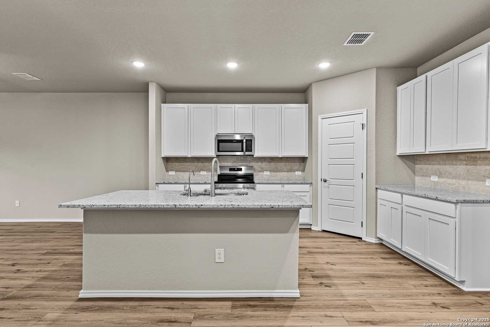 Modern kitchen with white shaker cabinets, granite island sink, stainless appliances in Davidson Homes The Douglas F, San Antonio