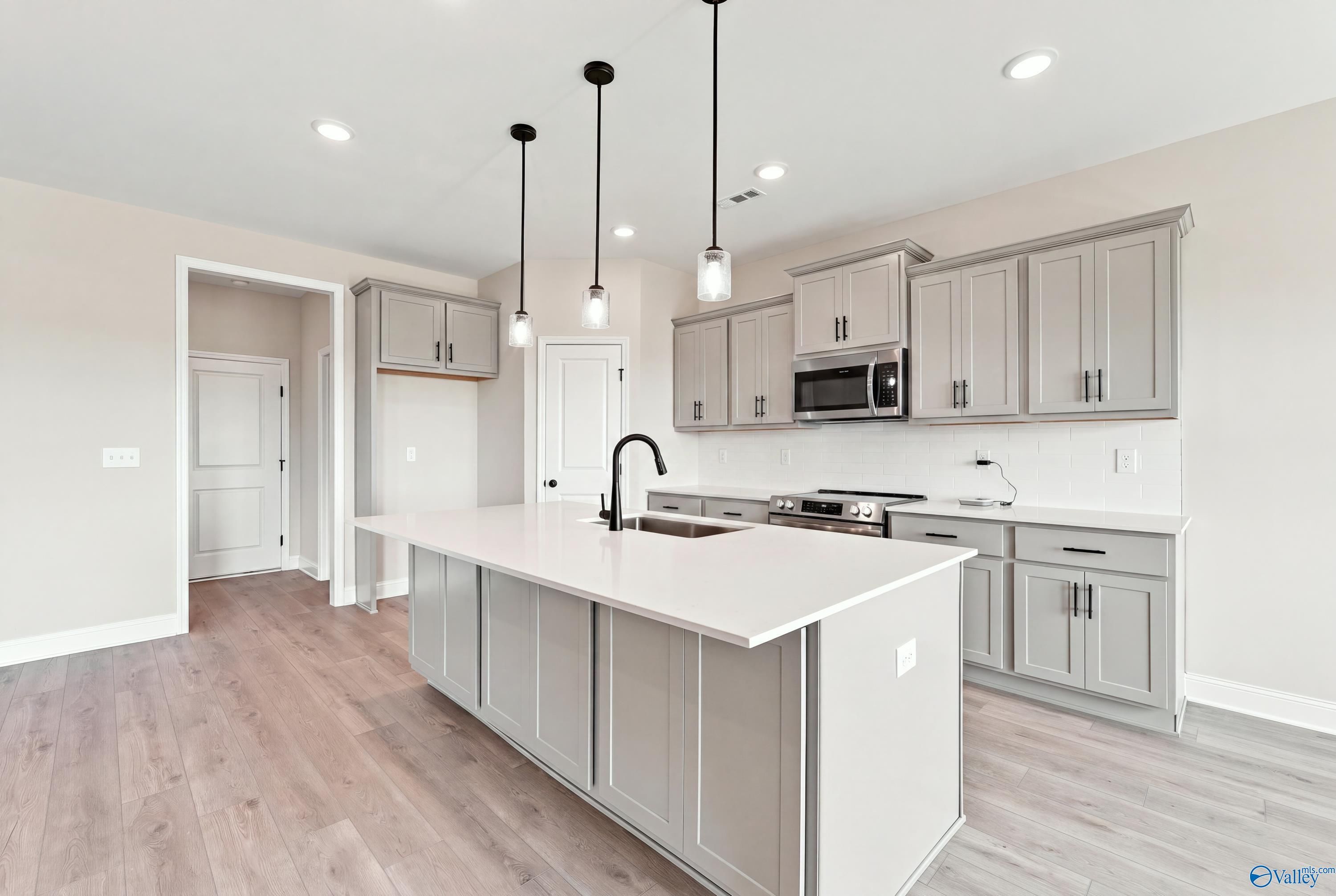 Kitchen island with sink, pendant lights, and gray shaker cabinets in Davidson Homes Montgomery D plan, Athens, Alabama