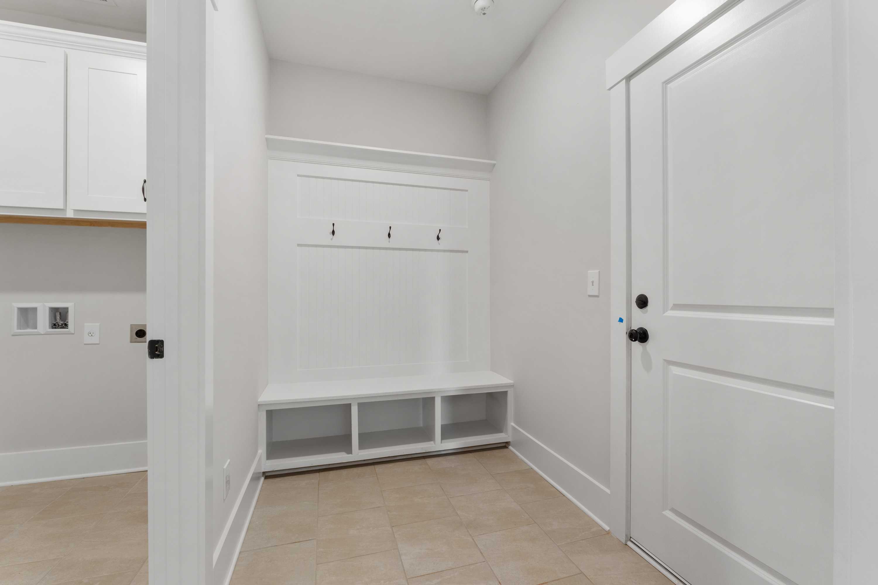 Spacious mudroom with built-in bench, coat hooks, and storage cabinets at The Villas at Barnett's Crossing in Madison, Alabama