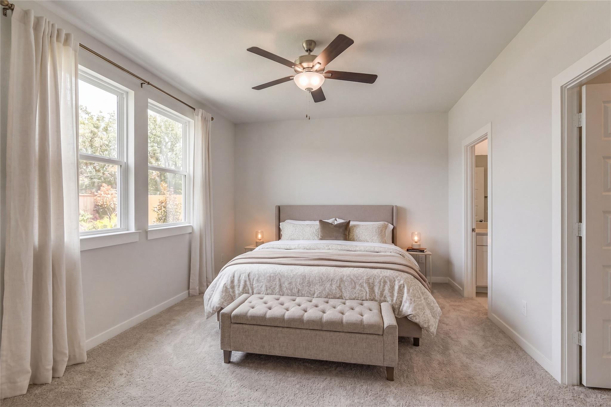 Tranquil master bedroom with king bed, ceiling fan, large windows, and ensuite bath in Davidson Homes The Frio G, Cleveland, Texas