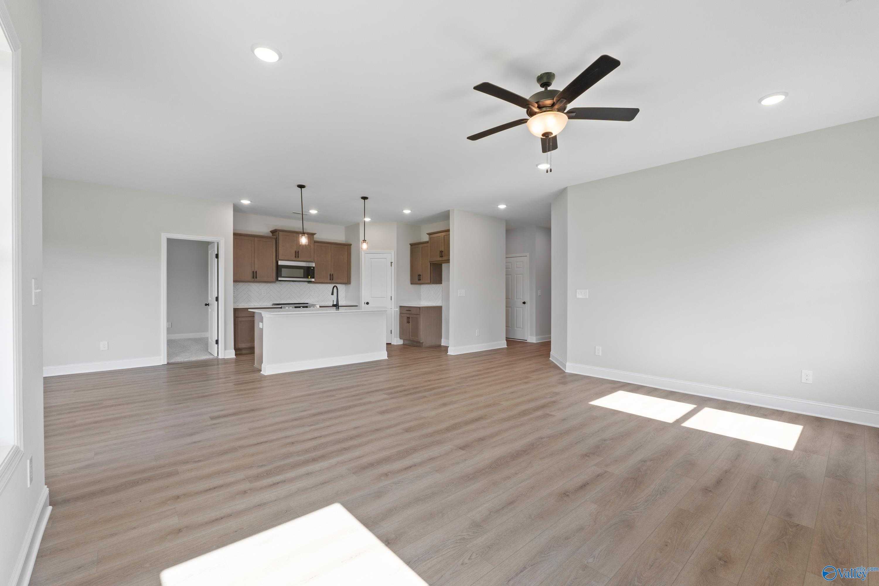 Spacious open-concept kitchen and living area with white shaker cabinets, large island, ceiling fan in 3-bedroom Davidson Homes The Franklin C, Hazel Green, AL